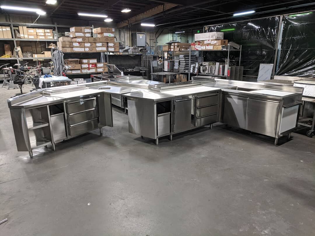 Angled chef's counter with refrigerated drawers, refrigerated raised pan rails, and insulated ice bins with recess for flush cutting boards.