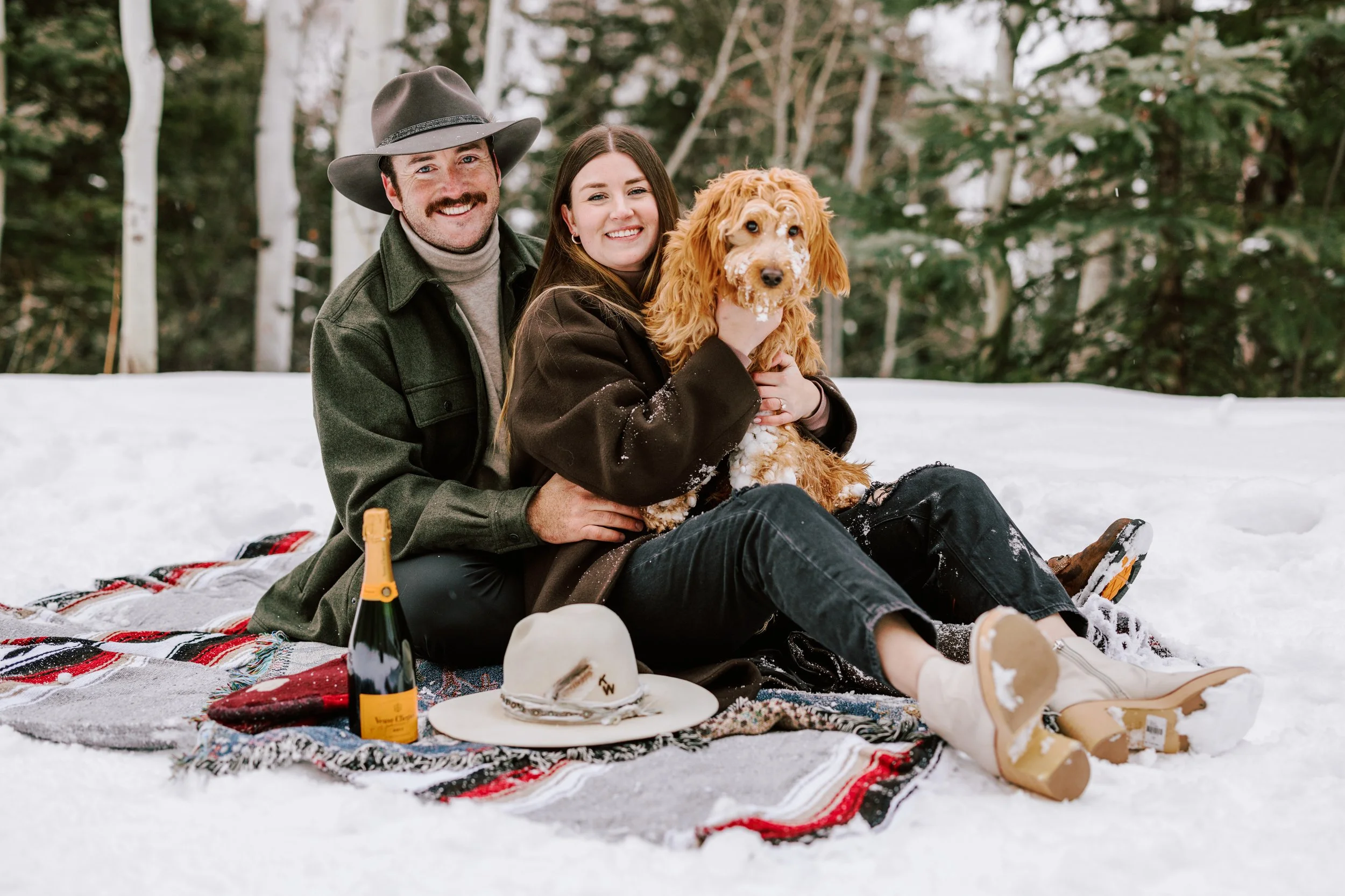 happy couple smiling with their dog during an engagement session in aspen, colorado