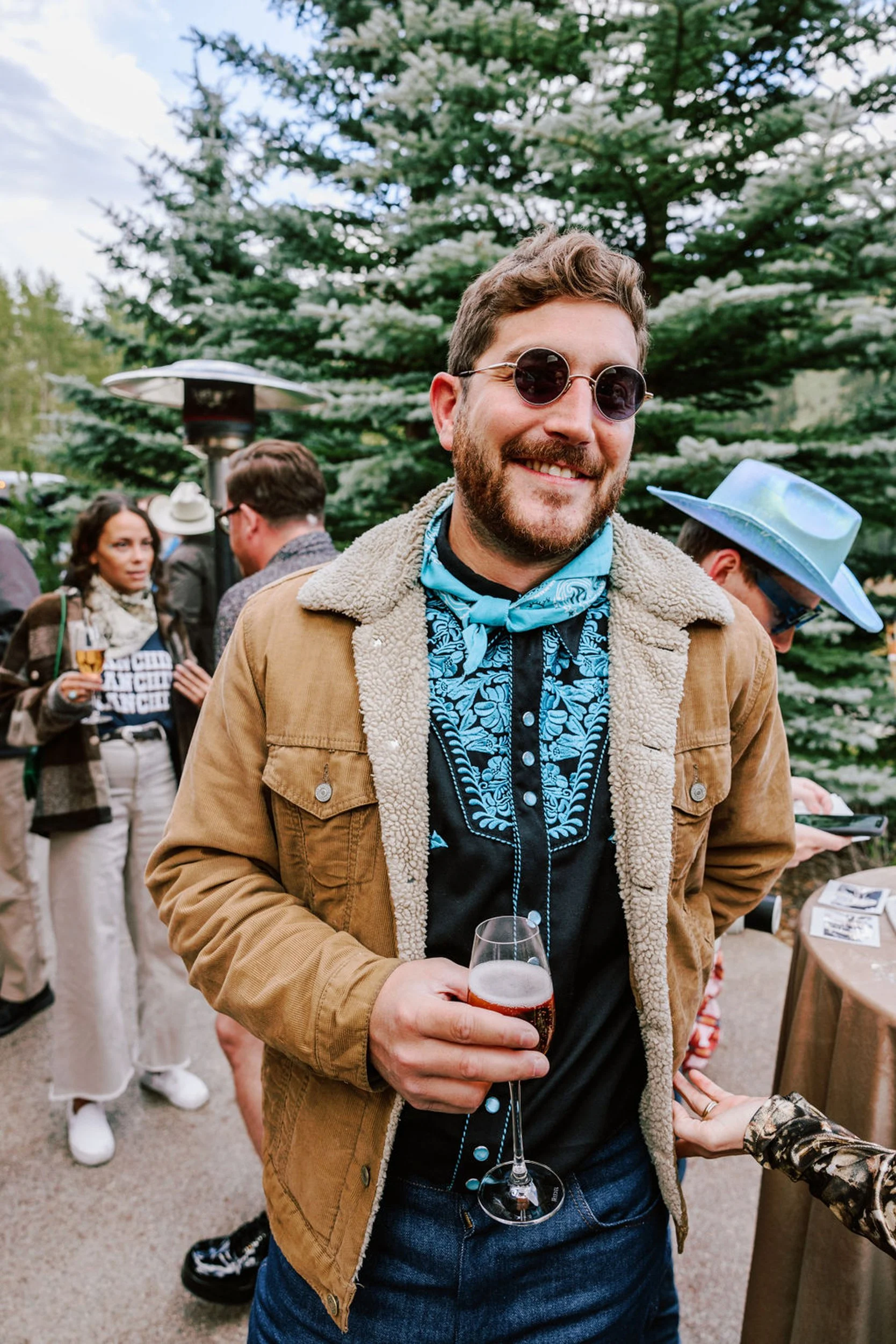 Bearded wedding guest in casual western style enjoying a drink at Pine Creek Cookhouse rodeo disco wedding in Aspen Colorado