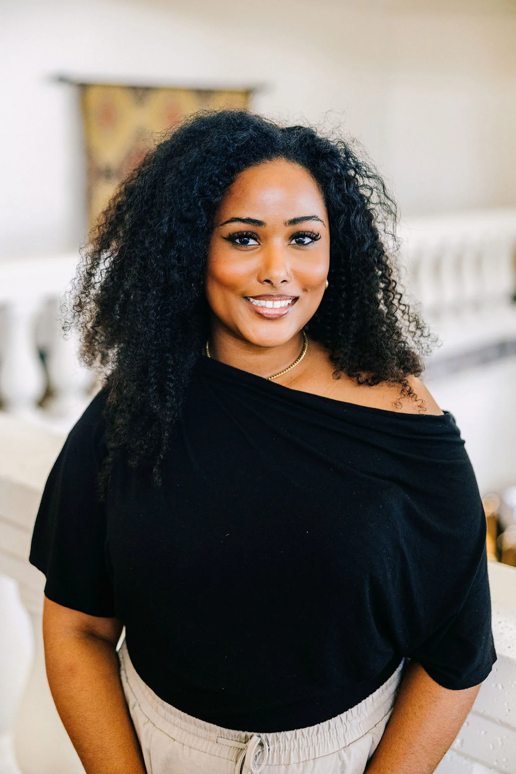 Denver professional headshot of a woman smiling with natural curls and an off shoulder top