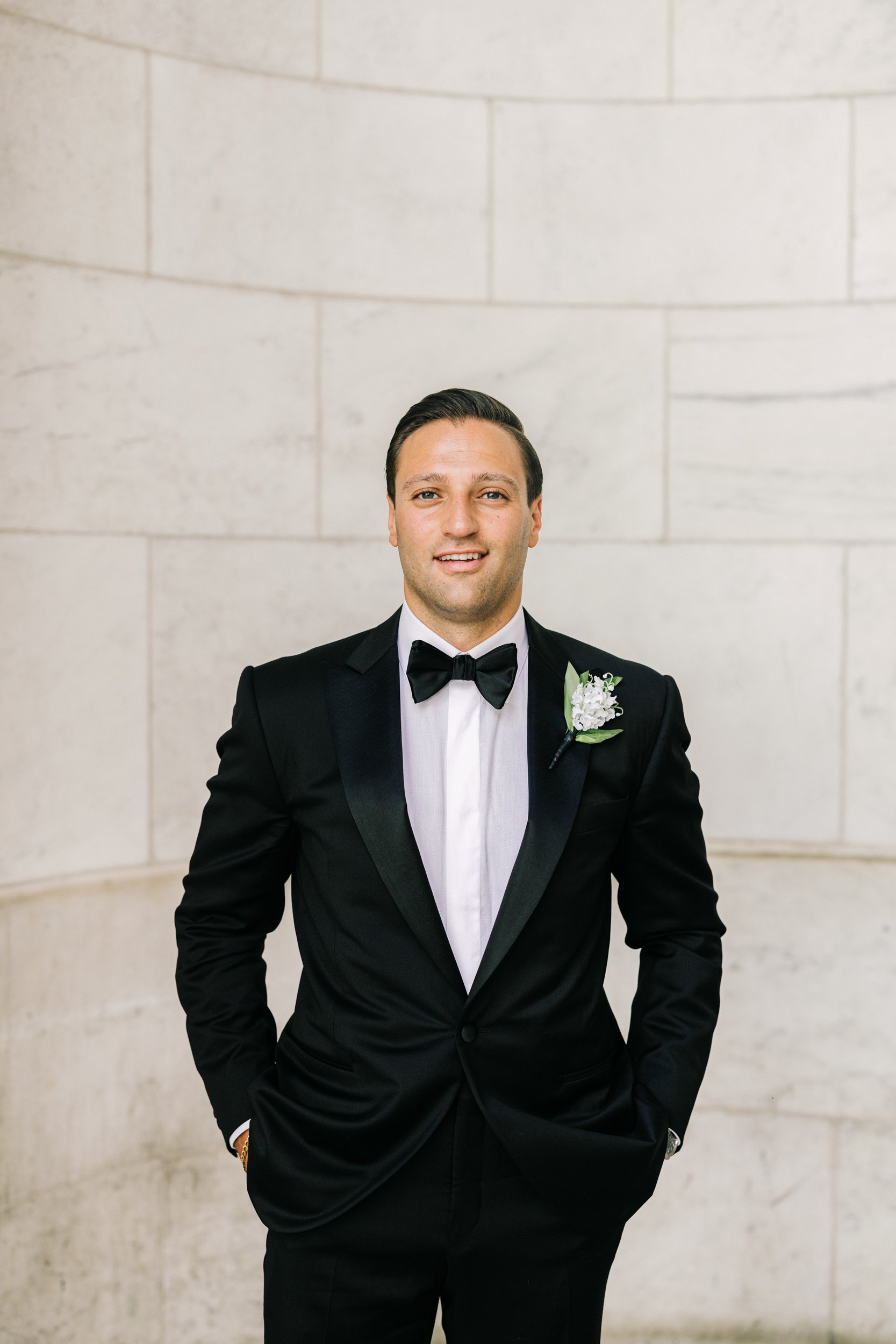 Groom solo portrait in a black tuxedo with boutonniere at the New York Public Library, NYC wedding