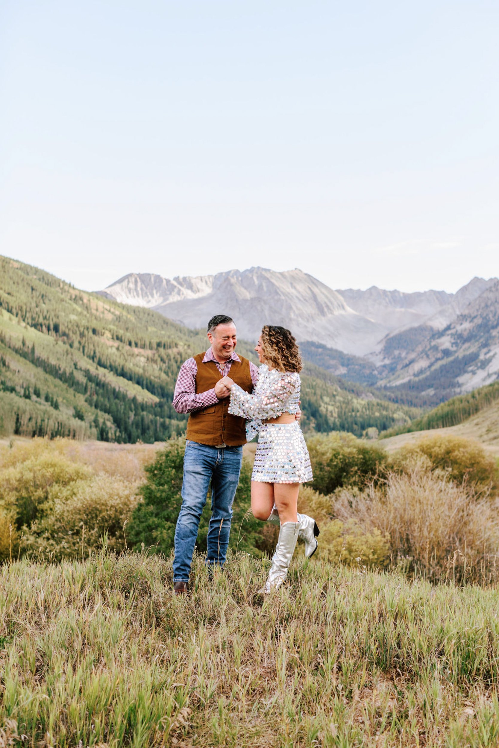 Wedding couple embracing in golden late-summer meadow with Elk Mountains visible behind them, Pine Creek Cookhouse Aspen area wedding photography