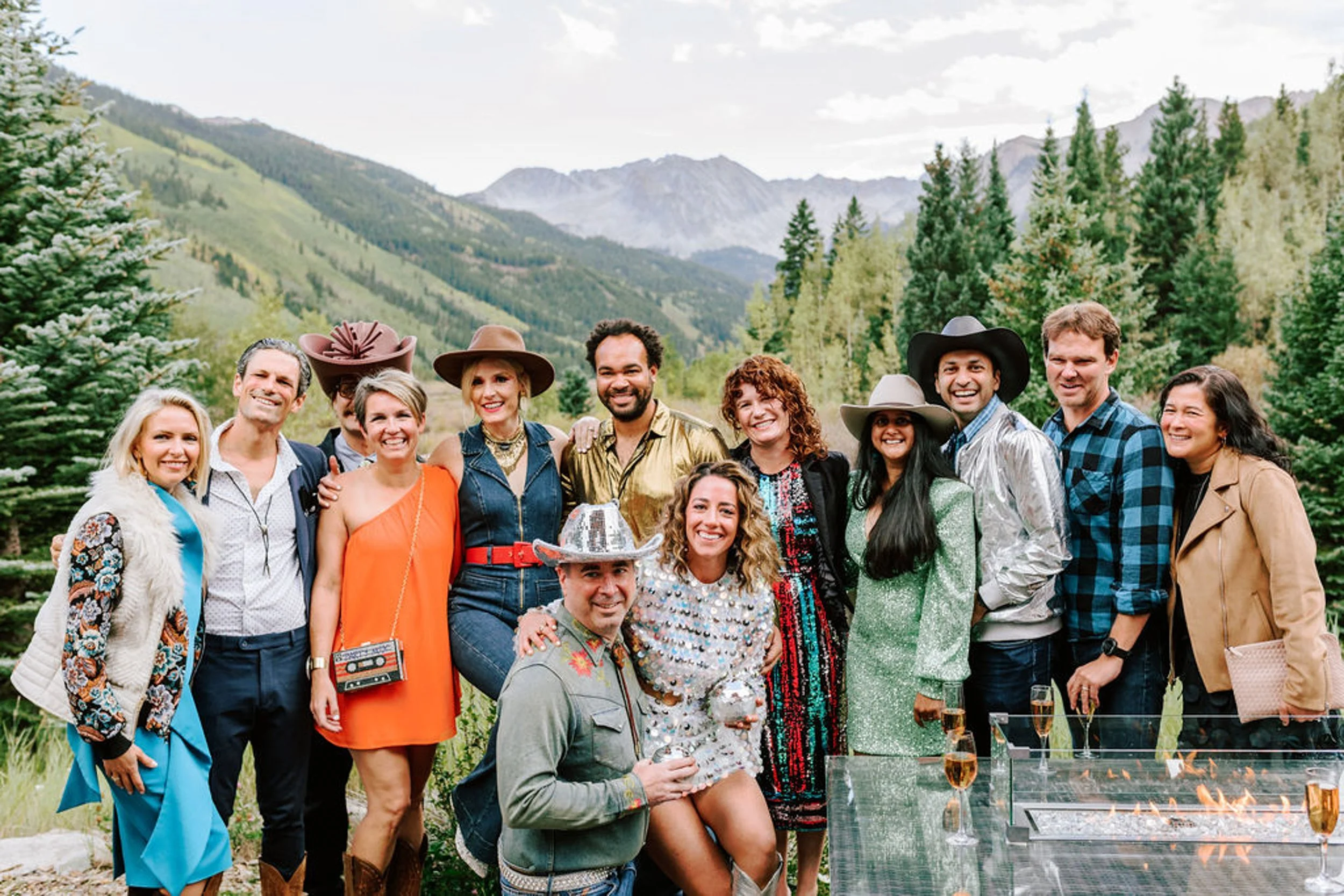 Large group of wedding guests in colorful western outfits with Colorado mountain backdrop at Pine Creek Cookhouse wedding in Aspen