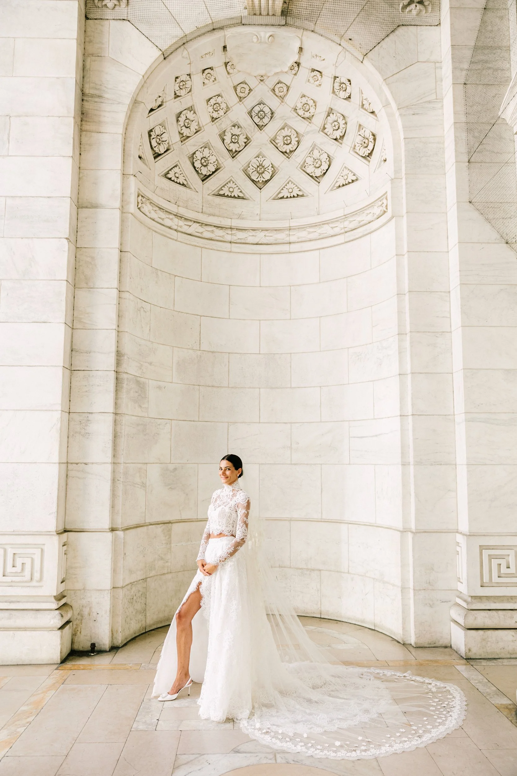 Bride in a full-length bridal portrait beneath the ornate architecture of the New York Public Library, NYC wedding
