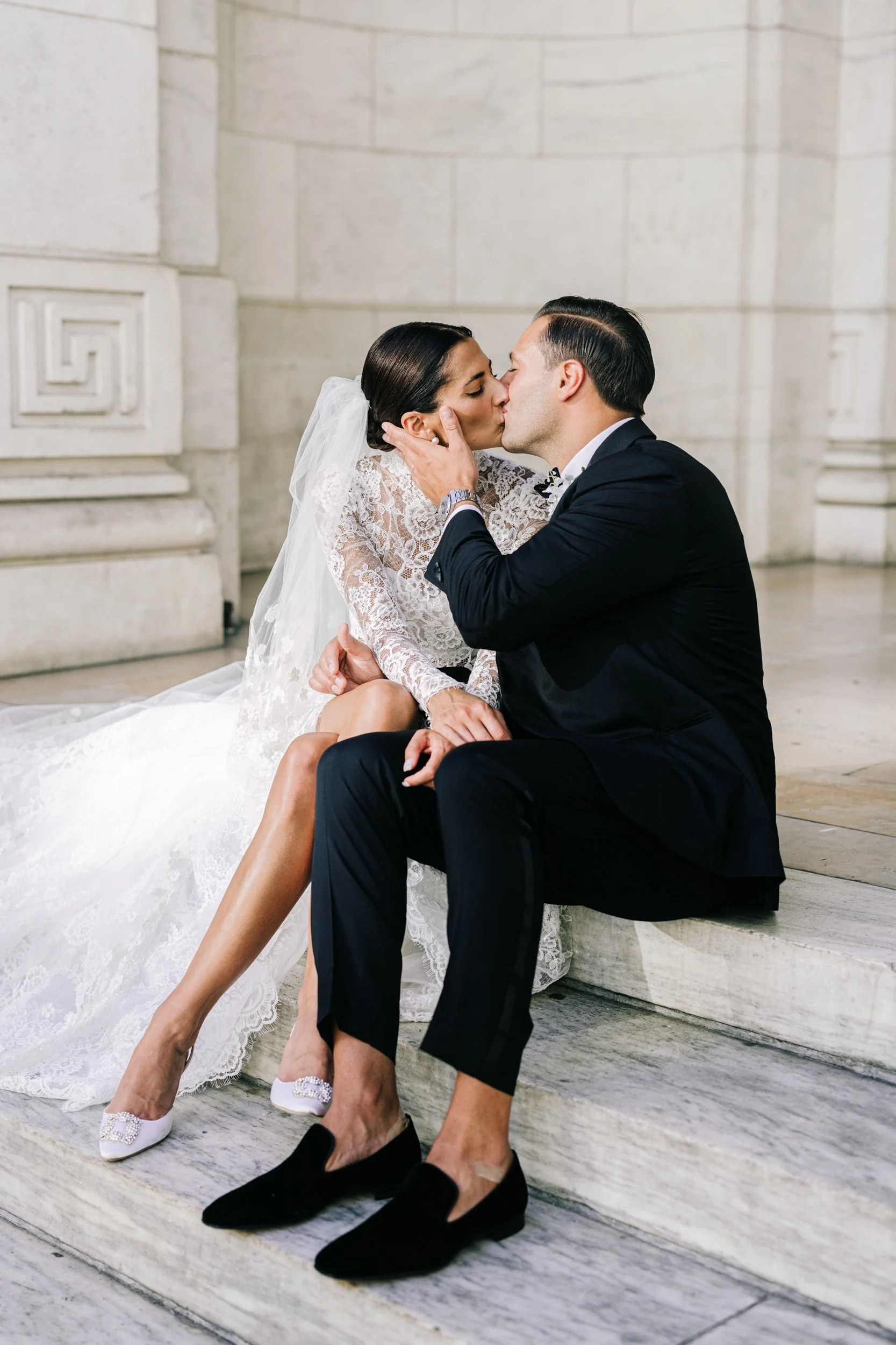 Bride leaning tenderly on the groom in an intimate seated portrait on the steps of the New York Public Library, NYC wedding