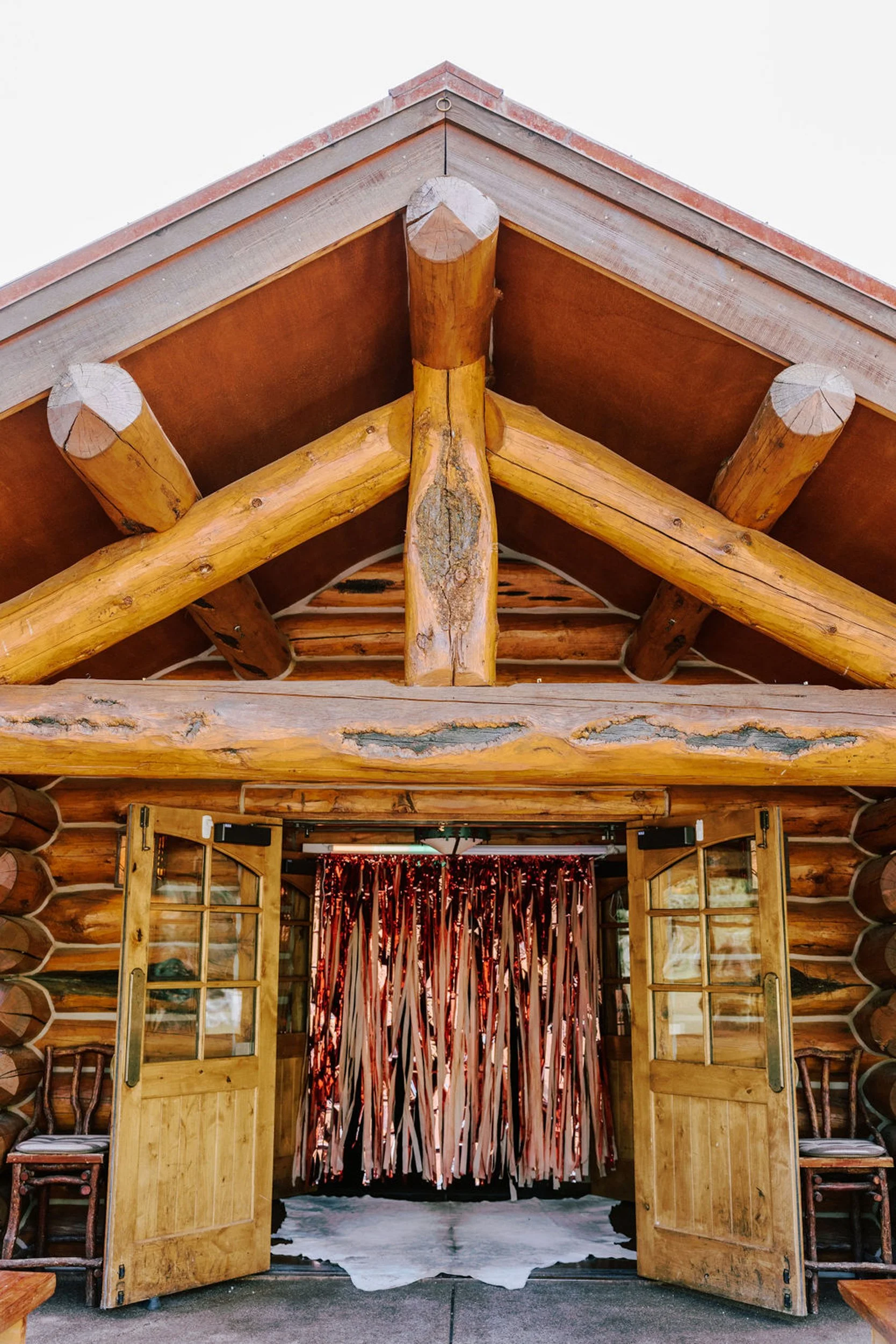 Pine Creek Cookhouse log timber entrance with pink fringe curtain decorated for a rodeo disco wedding reception, Aspen Colorado mountain wedding venue