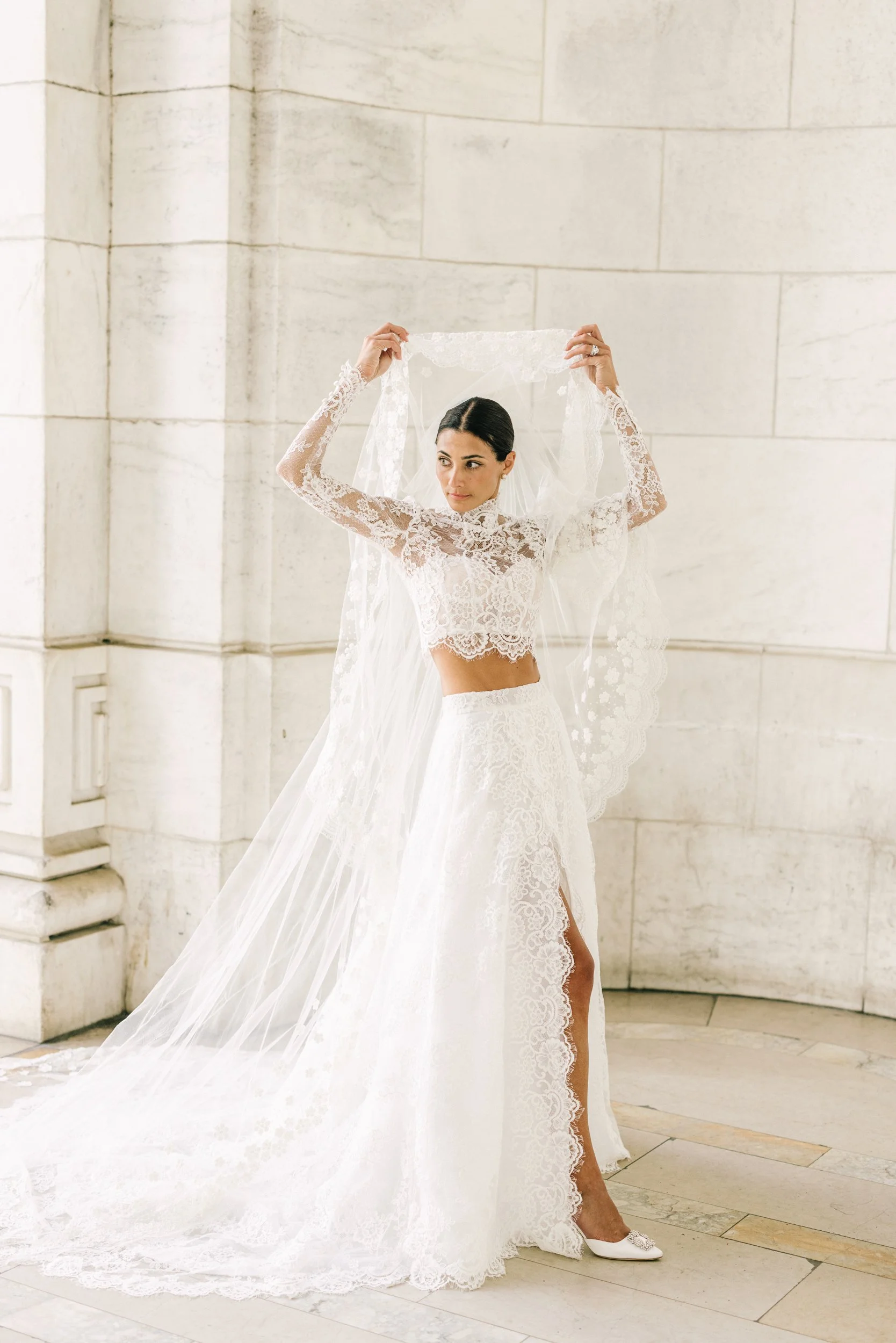 Bride raising her arms to lift her veil in a joyful bridal portrait at the New York Public Library, NYC wedding