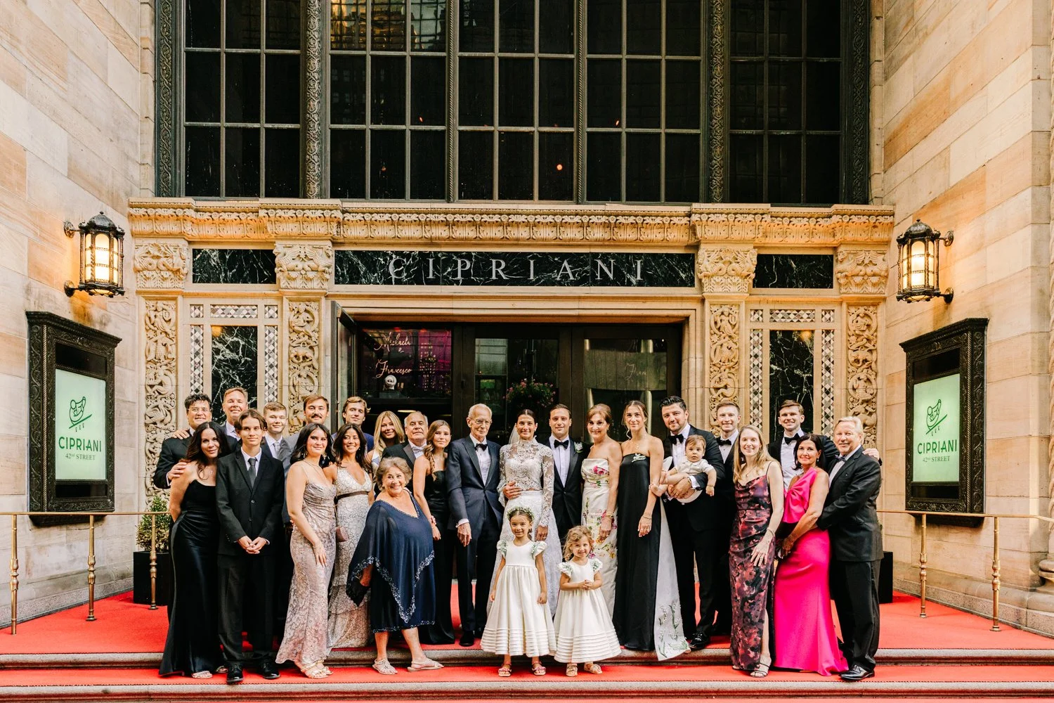 Bride and groom standing in front of Cipriani 42nd Street in New York City on their wedding day with their family