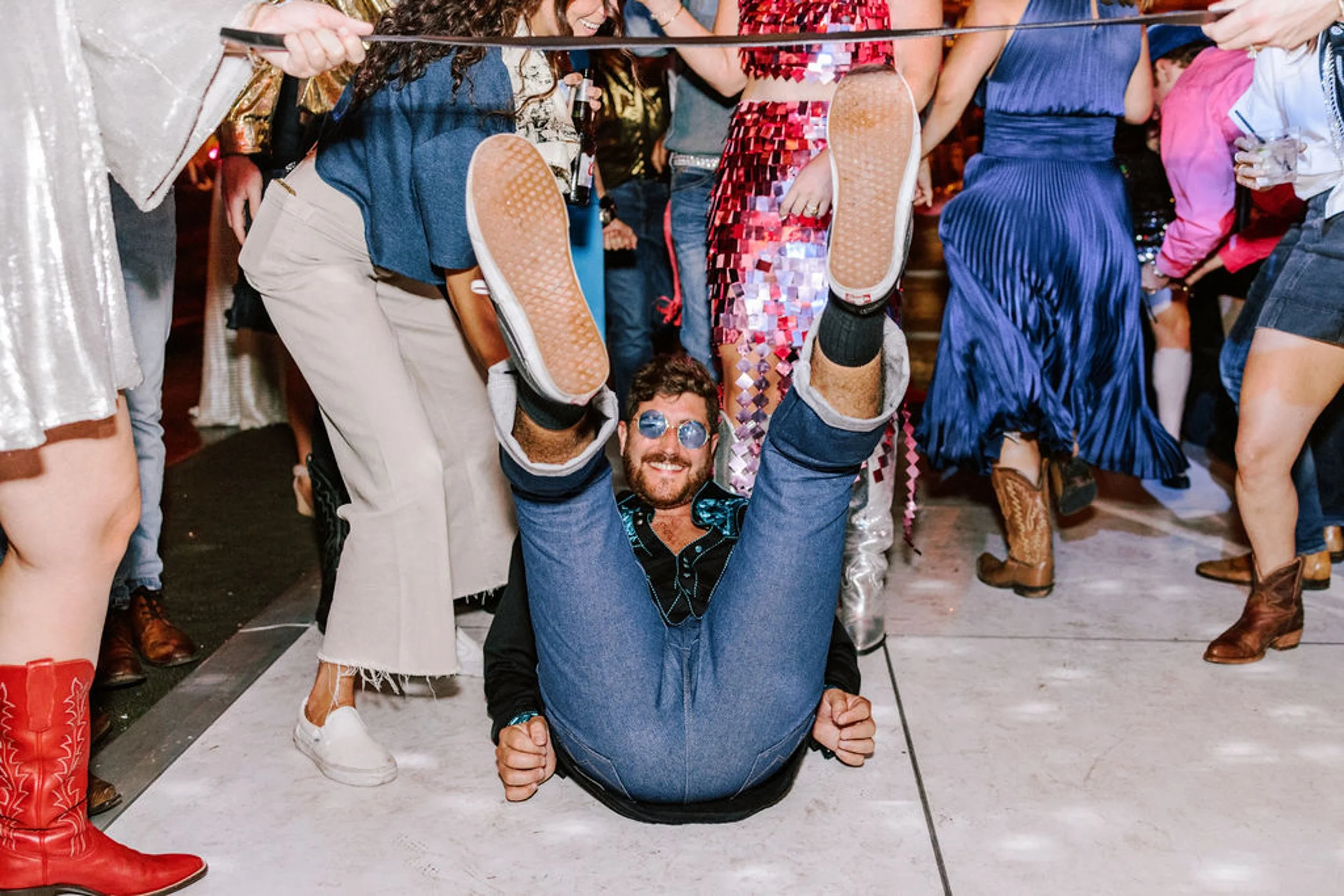 Wedding guest performing acrobatic dance move on the floor surrounded by dancing guests at lively Pine Creek Cookhouse rodeo disco reception in Colorado