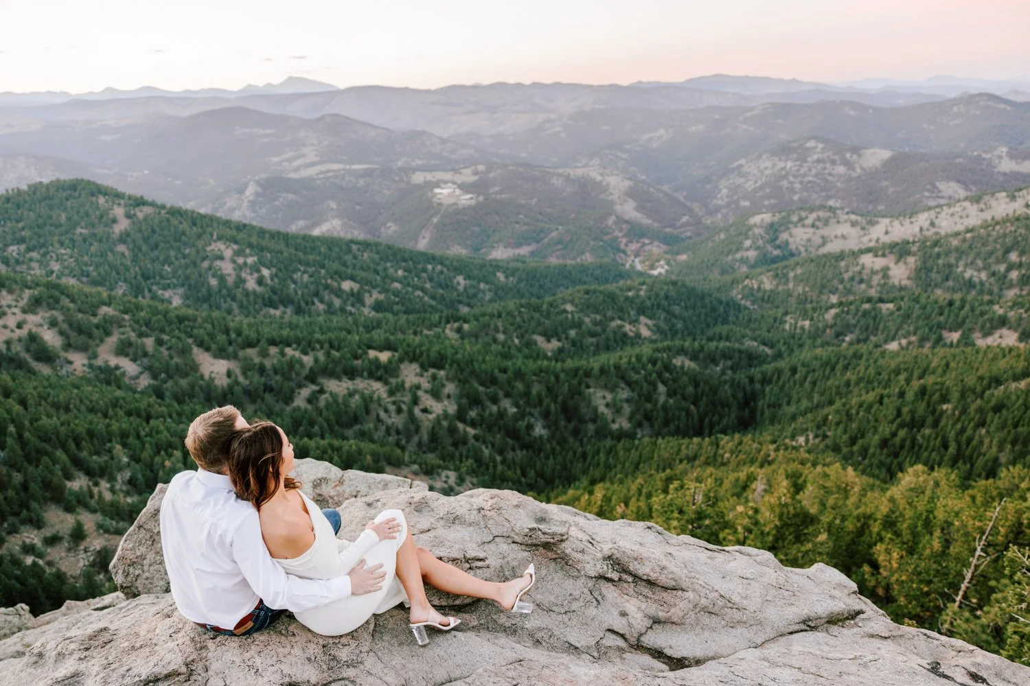 happy couple smiling with mountains in the background during their engagement session in boulder, colorado