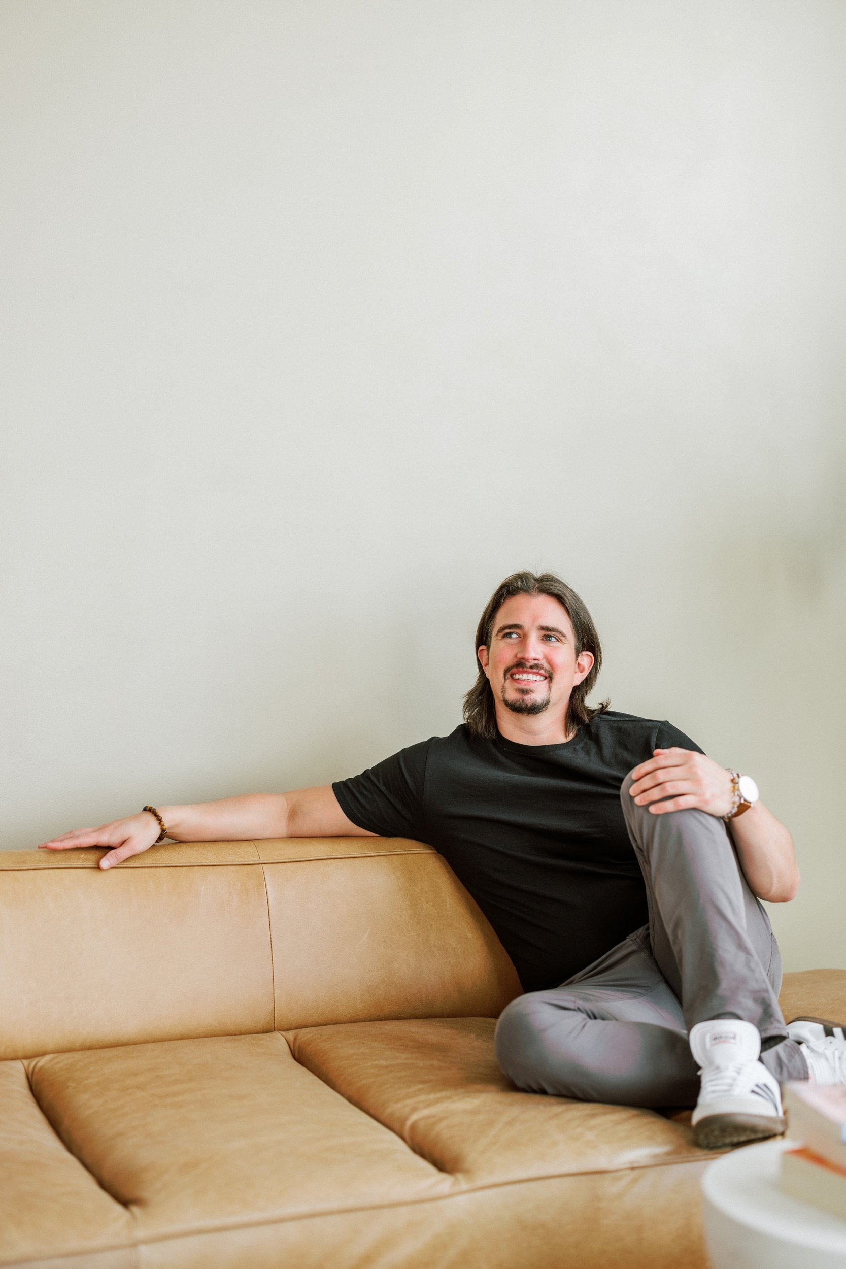 Relaxed editorial headshot of a man seated on a couch during a Denver headshot session