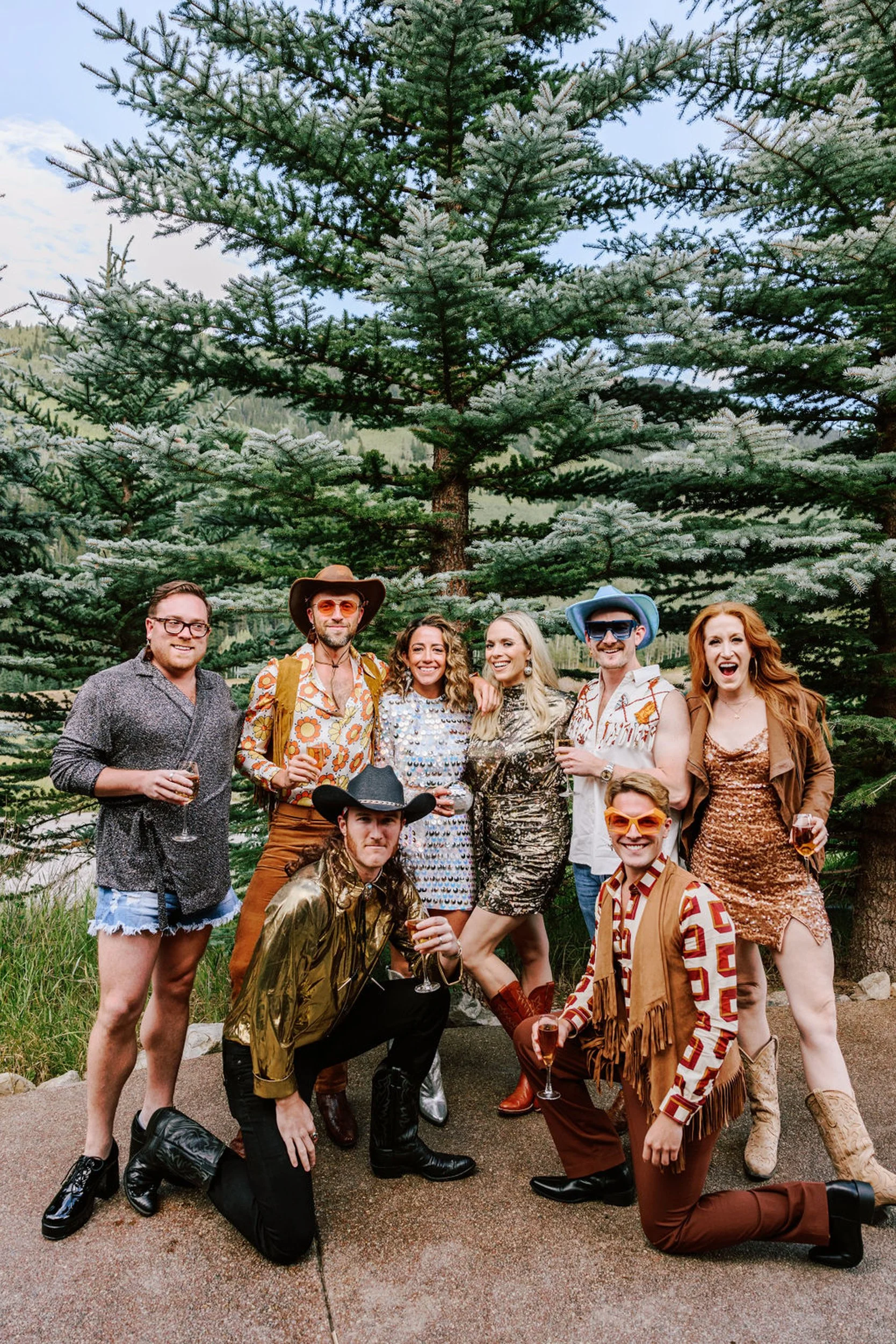 Full wedding party in western and boho rodeo outfits posing together outdoors at Pine Creek Cookhouse wedding in Aspen Colorado