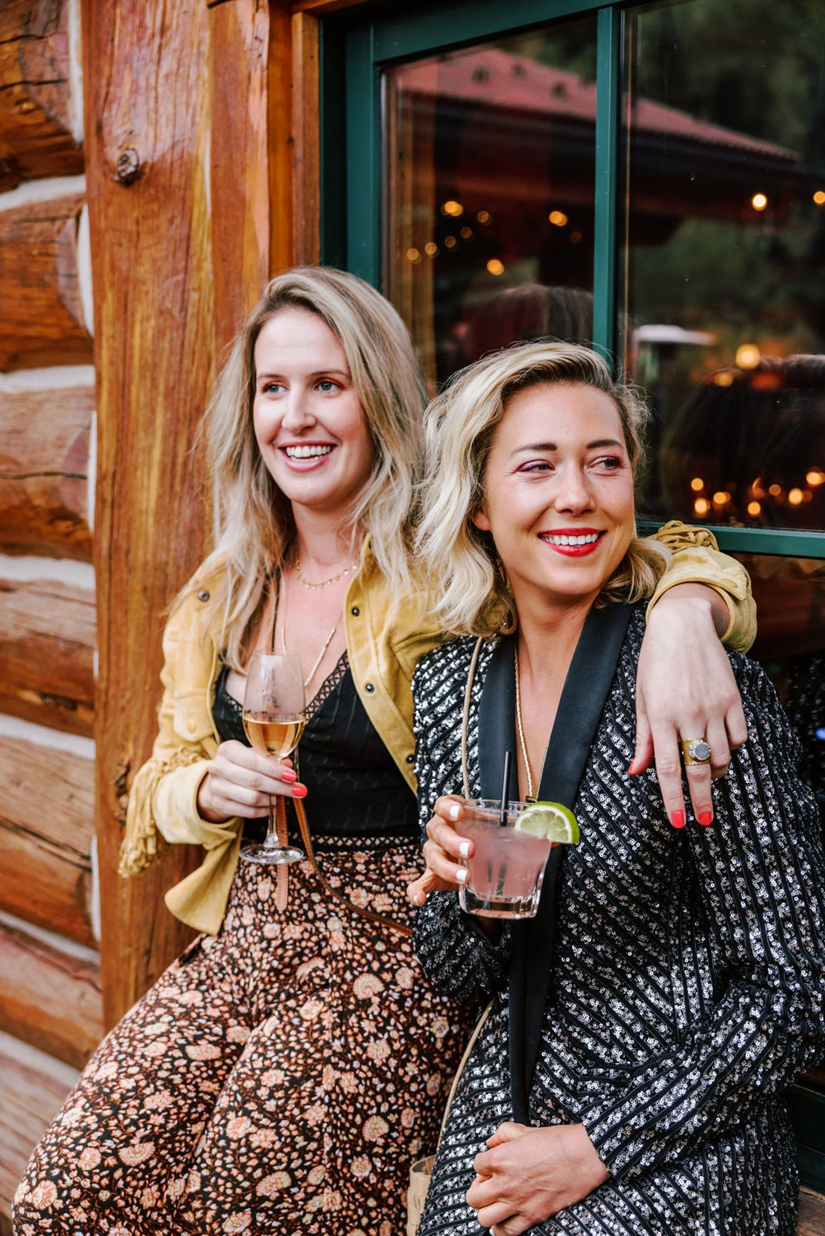 Two wedding guests in glamorous outfits enjoying cocktails at Pine Creek Cookhouse rodeo disco reception in Aspen Colorado