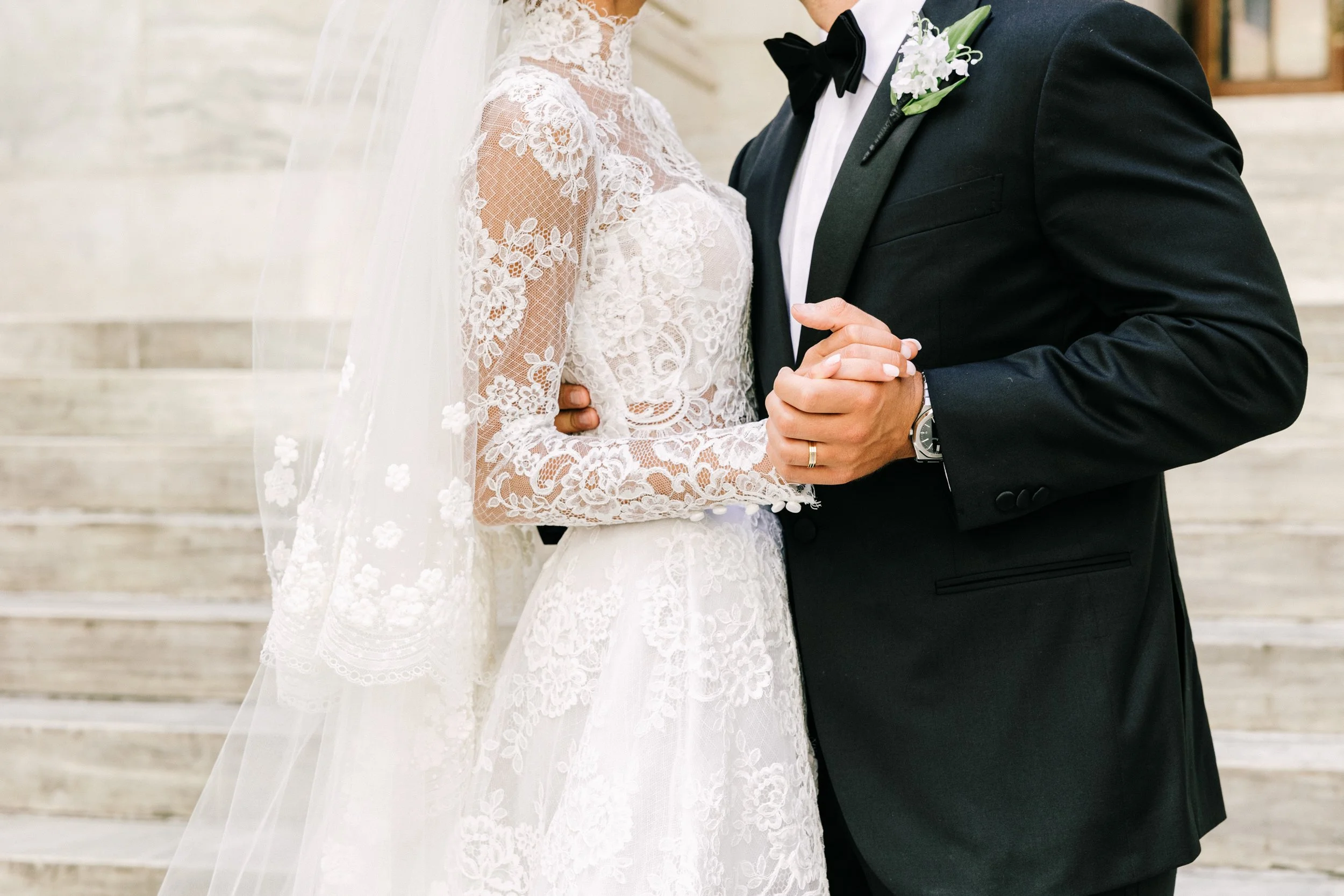 Close-up detail of bride and groom holding hands on the steps of the New York Public Library, NYC wedding