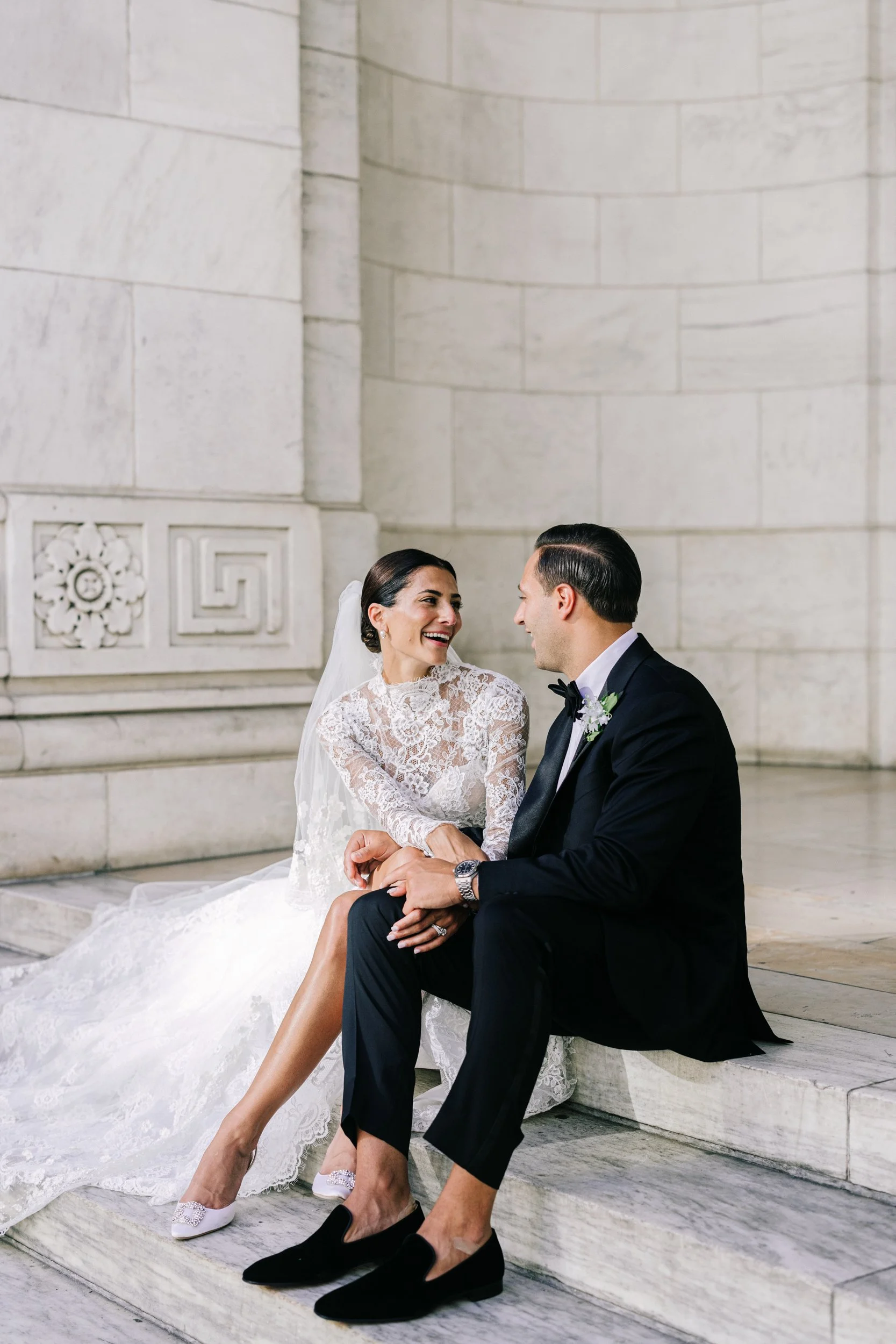 Bride and groom sharing a candid laugh while sitting on the steps of the New York Public Library, NYC wedding