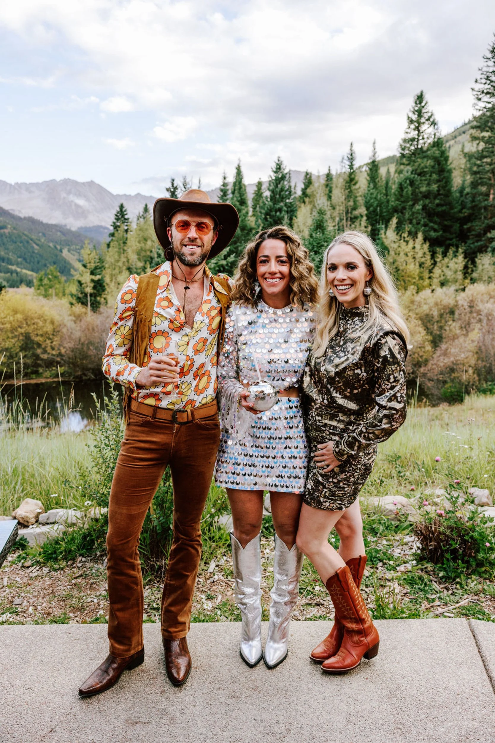 Wedding guests in western fringe and white cowboy boots posing with mountain backdrop at Pine Creek Cookhouse rodeo disco wedding Aspen Colorado