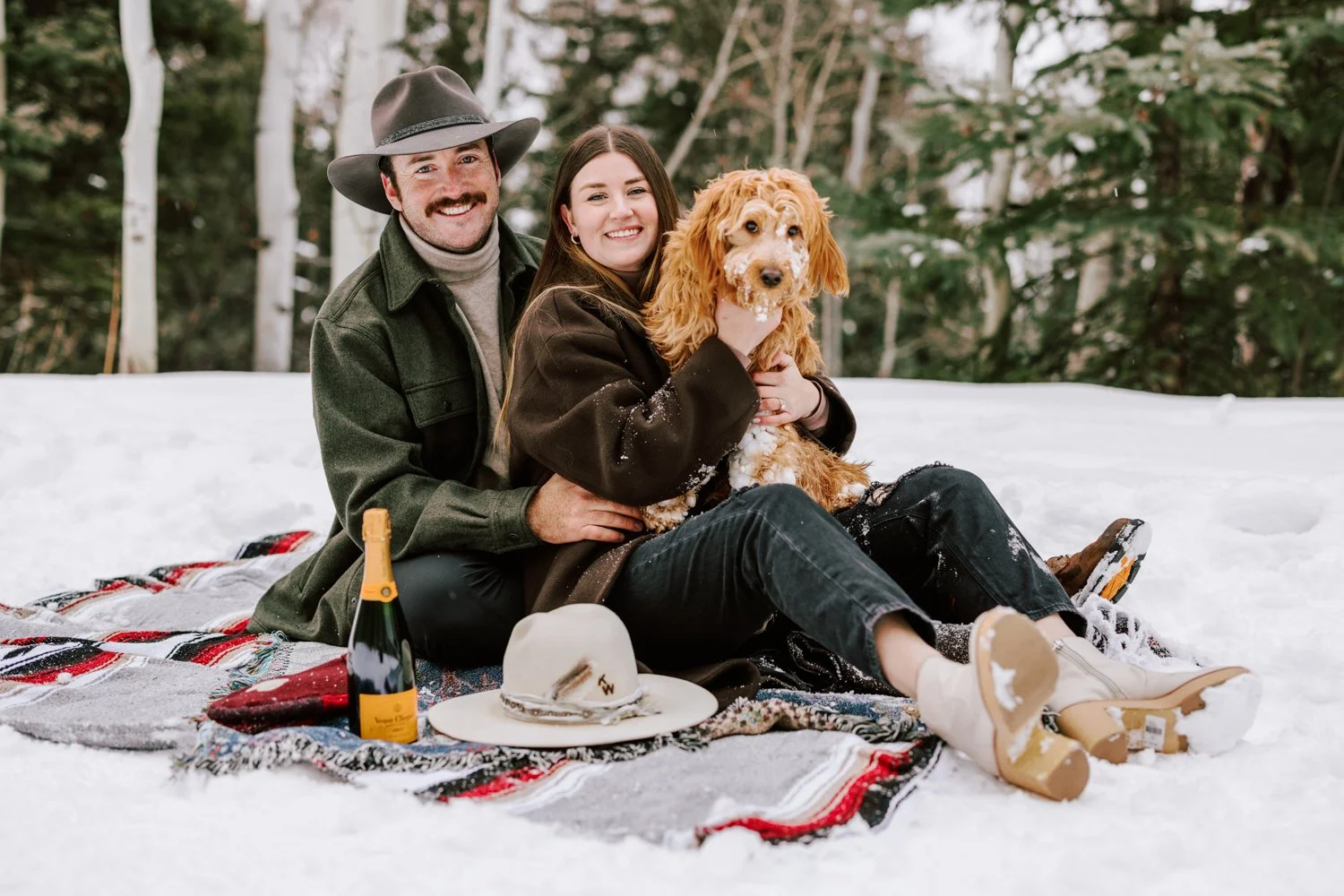 couple smiling with their dog after getting engaged in colorado