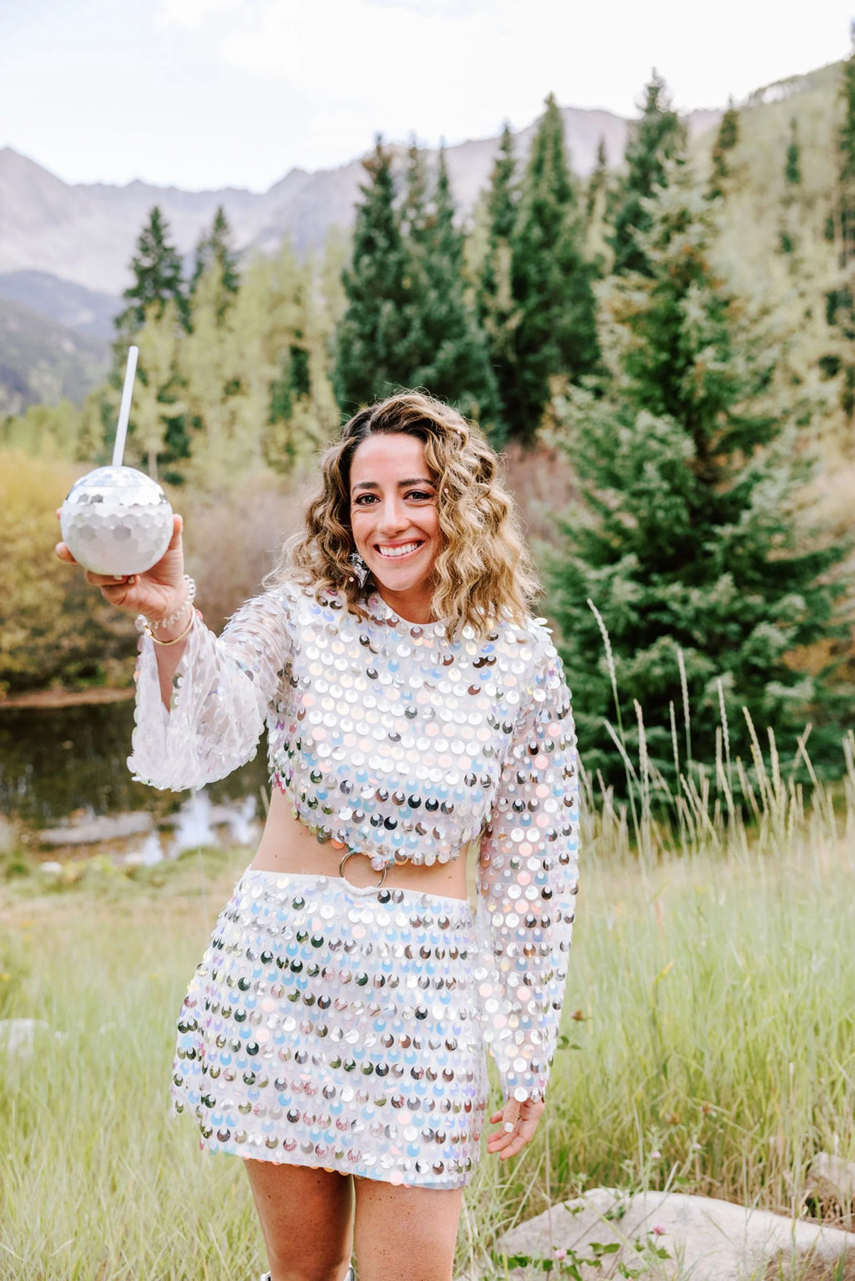Bride laughing in silver sequin two-piece reception outfit holding a disco ball at Pine Creek Cookhouse, Colorado mountain wedding photography by Betsi Ewing