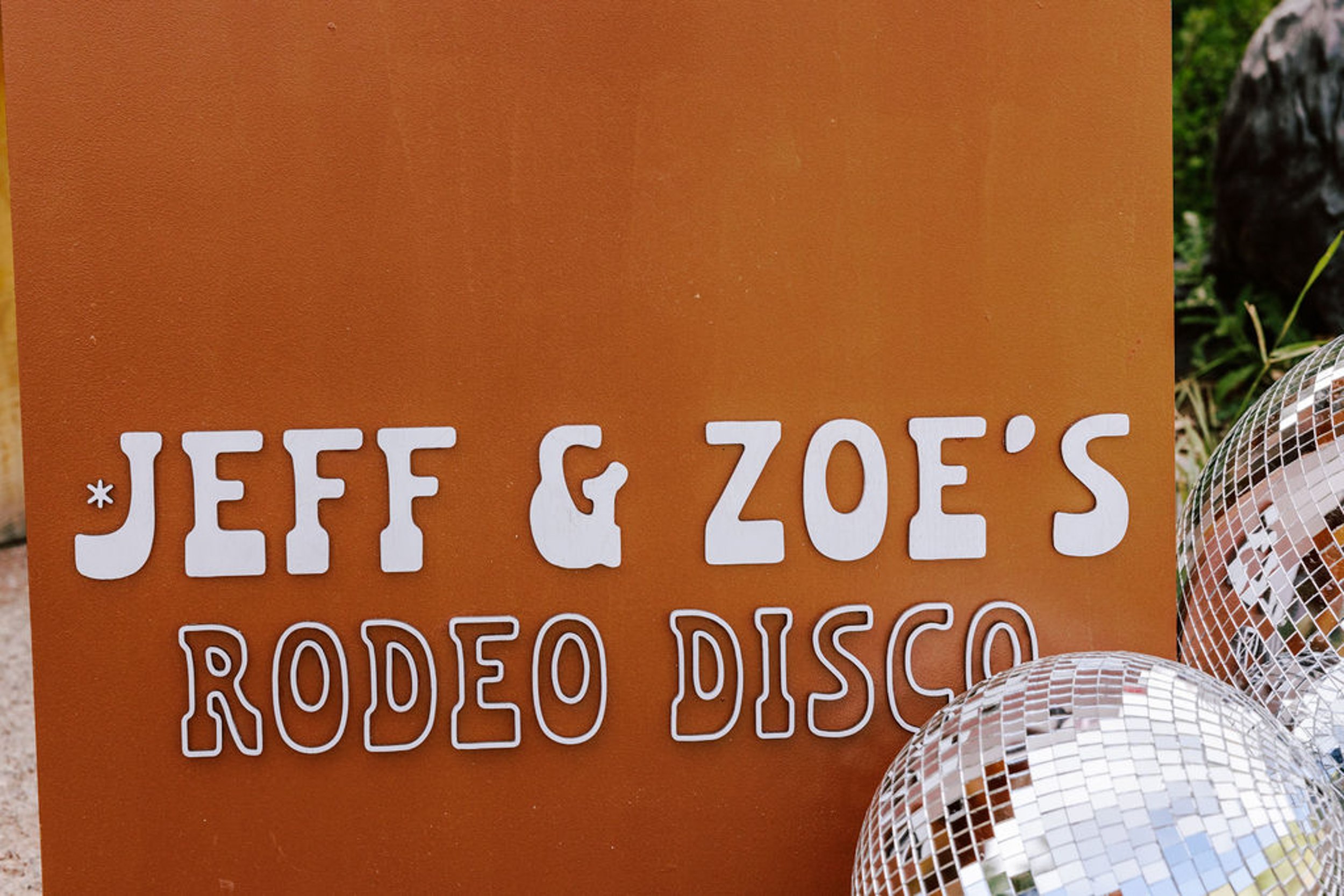 Jeff and Zoe's Rodeo Disco wedding reception sign on terracotta brown with disco ball, custom signage detail at Pine Creek Cookhouse wedding in Aspen Colorado