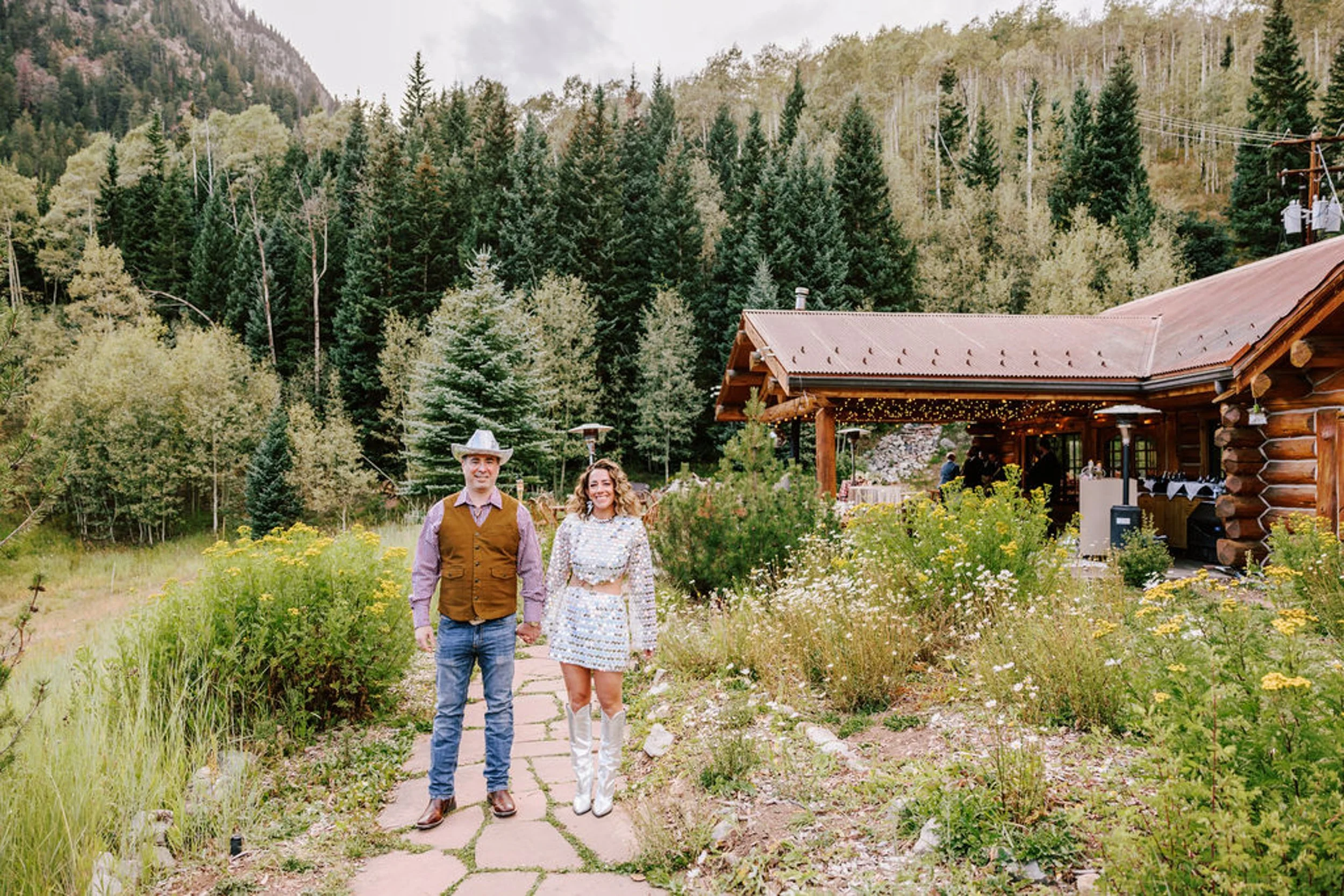 Bride and groom in front of Pine Creek Cookhouse surrounded by summer wildflowers and pine trees, Ashcroft Colorado wedding photography by Betsi Ewing