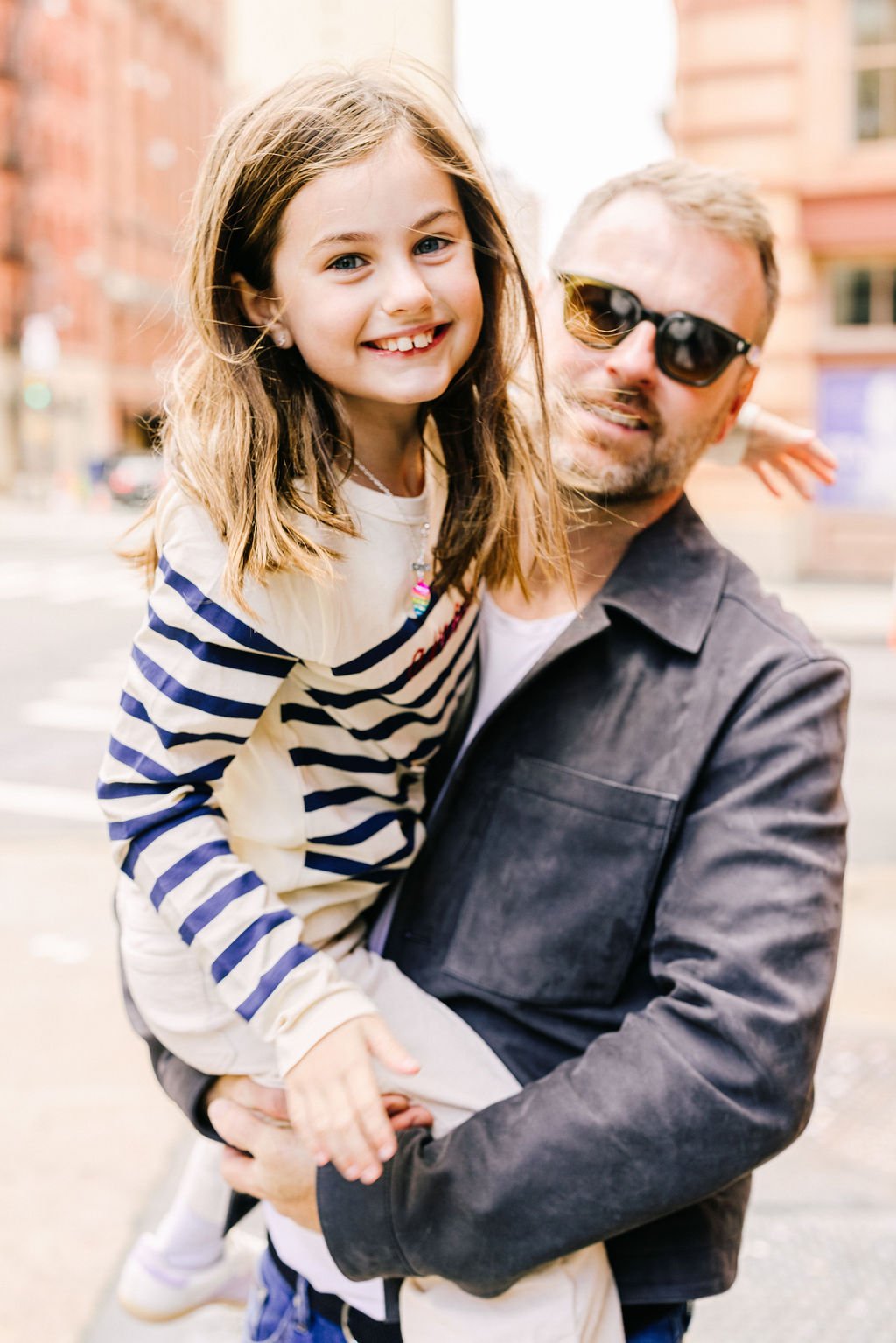 Father and daughter smiling during a NYC family photography session on a city street