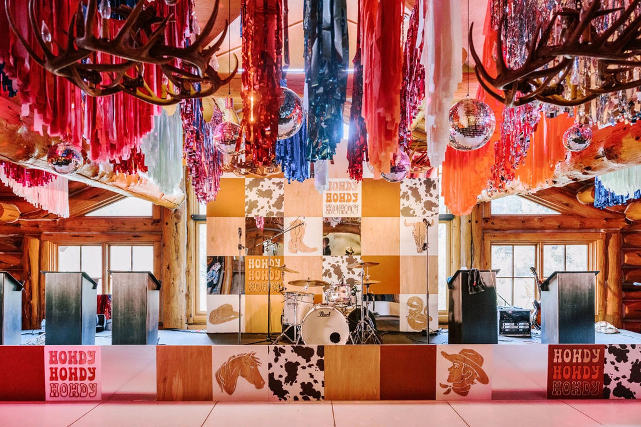 Pine Creek Cookhouse wedding reception hall decorated with colorful fringe streamers, disco balls, and rodeo disco wedding menus on tables, Aspen Colorado mountain wedding venue