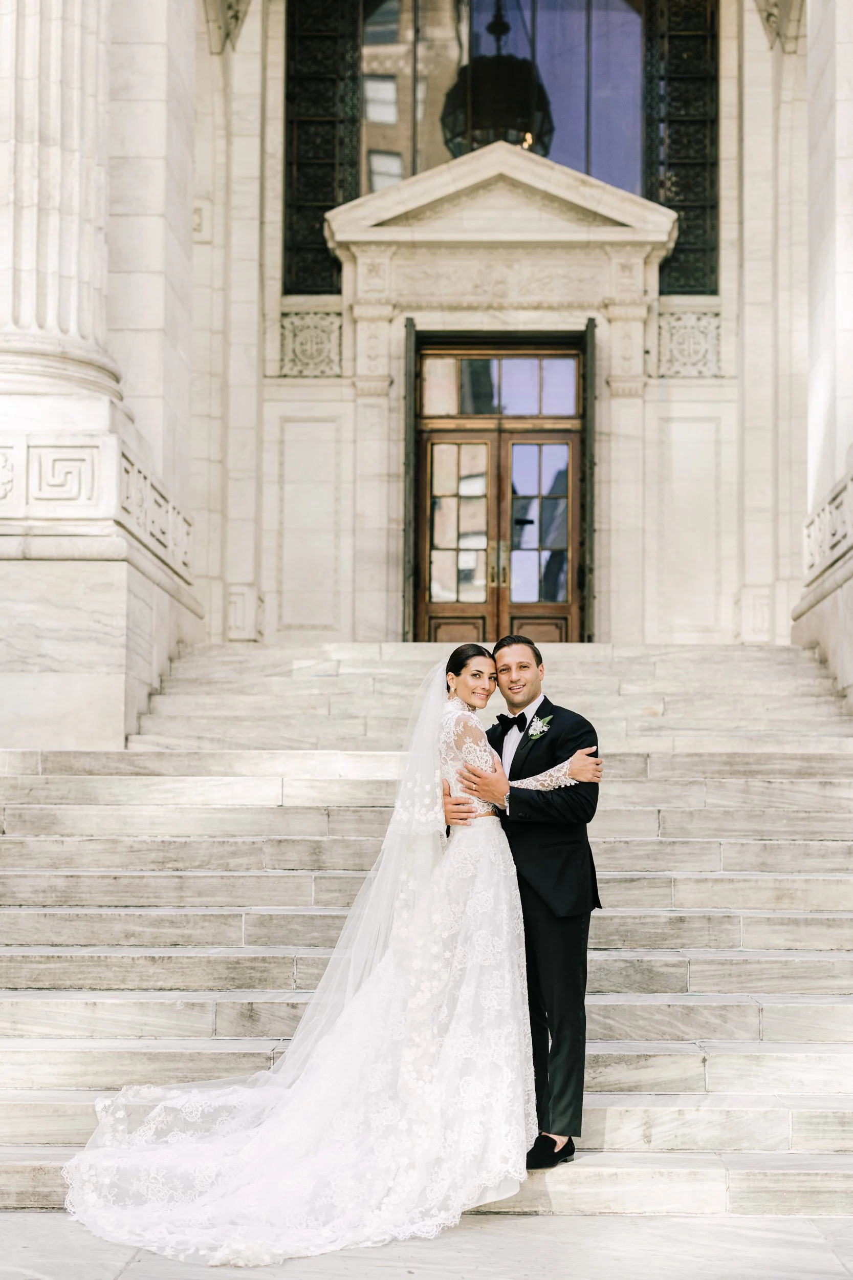 Bride and groom standing together on the iconic steps of the New York Public Library with grand columns, NYC wedding