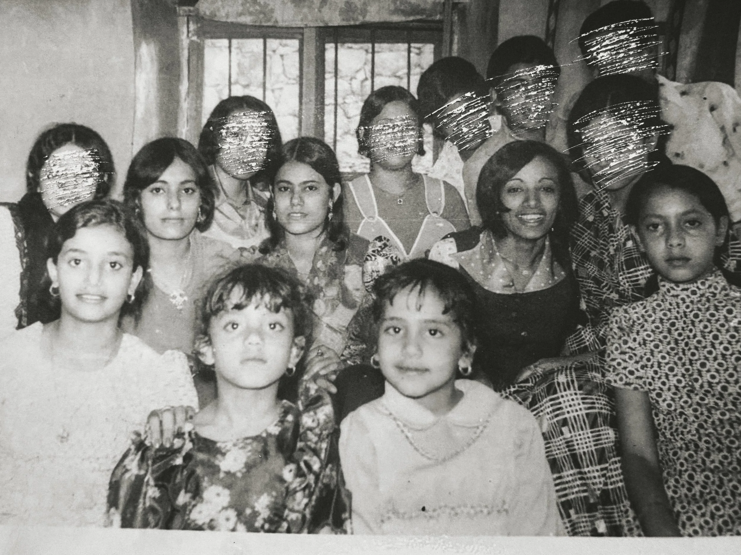Still image from the artists' short film. A black and white group photo of young girls and women. Some of the women's faces are scored out.