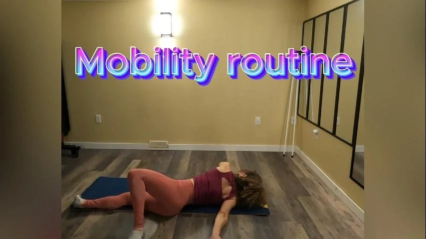 A woman lying on her side on an exercise mat, practicing mobility exercises in a room with beige walls and wooden flooring. The text 'Mobility routine' is displayed in colorful, bold font at the top of the image.