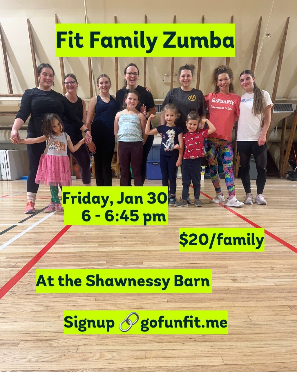Group of women and children posing together in a gymnasium with wooden flooring and exercise equipment in the background, promoting a Fit Family Zumba event.