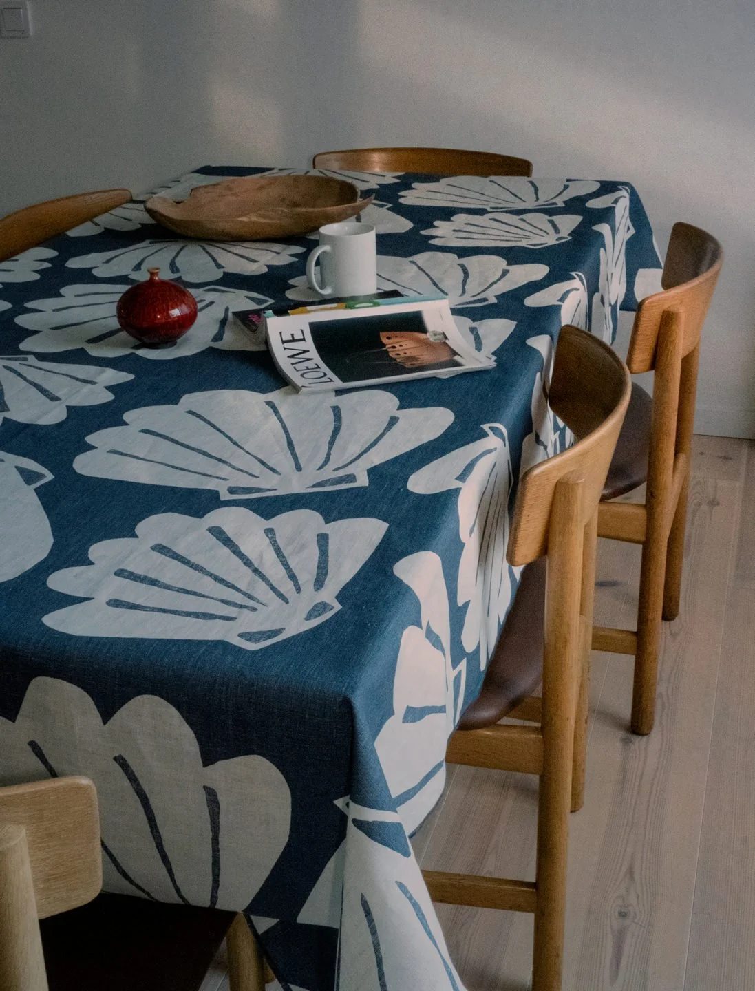 Fine Little Day Shell blue linen table cloth on a vintage table, surrounded by wooden chairs.