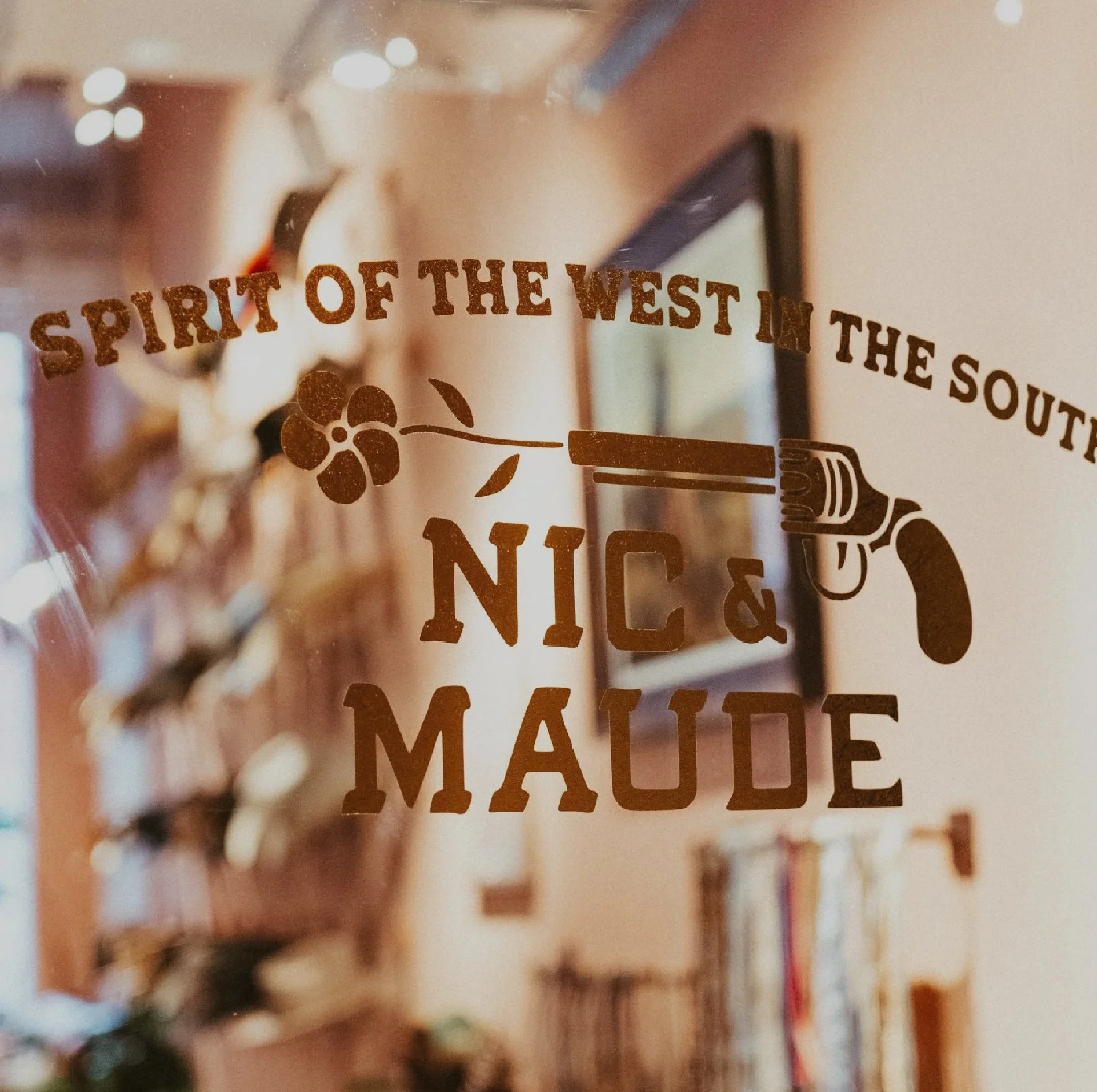 Text on glass that reads, "spirit of the west in the south, Nic & Maude"