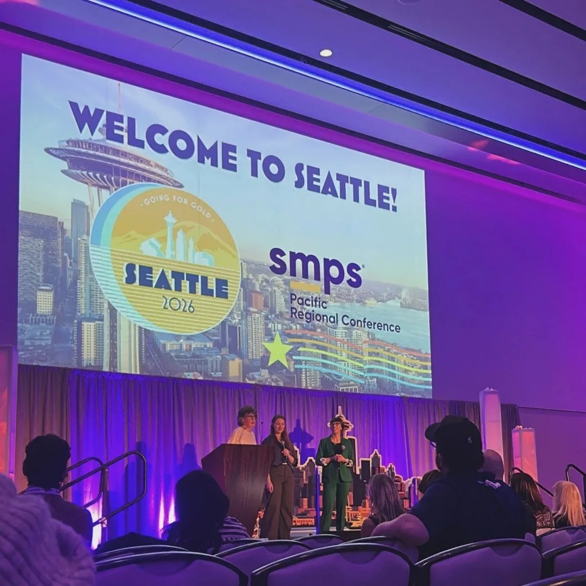 A welcome slide for the SMPS PRC conference with three women standing on a stage.