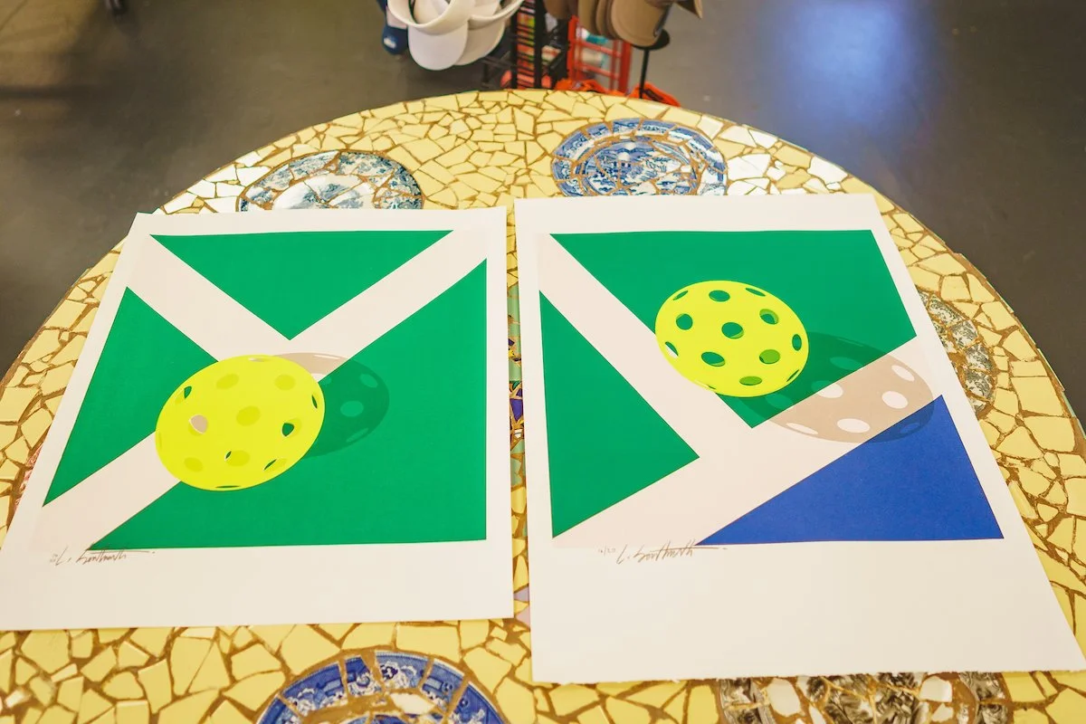 Two prints of Georgia flags with a yellow golf ball on them, placed on a mosaic table.