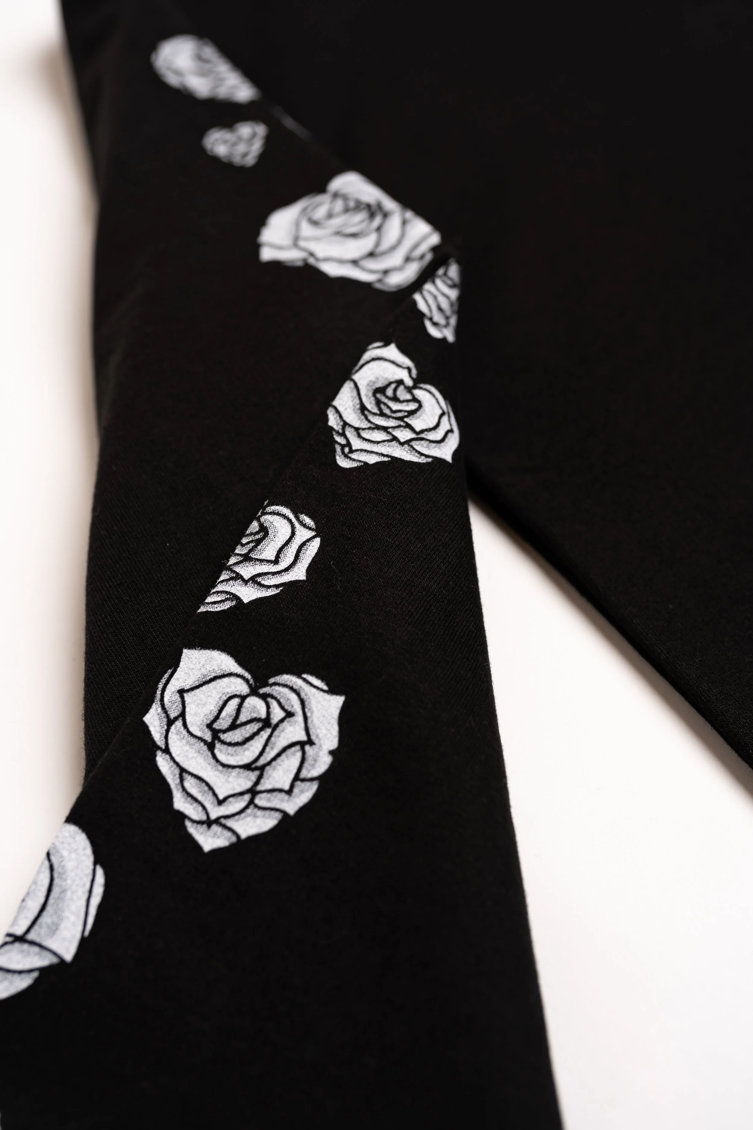Close-up of black fabric with white rose pattern on a diagonal fold.