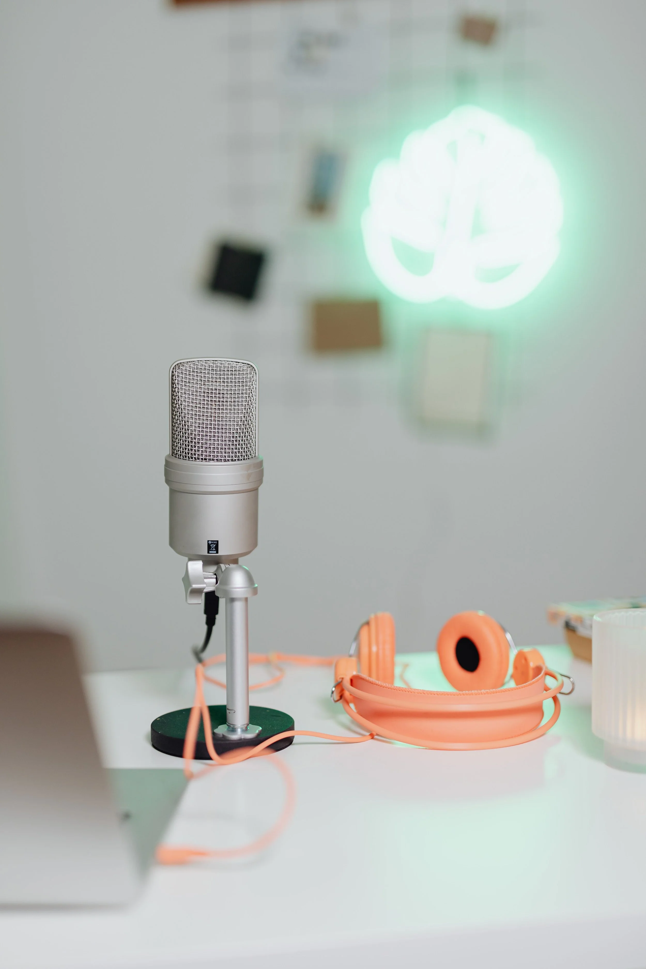 A podcast microphone next to a pair of orange headphones