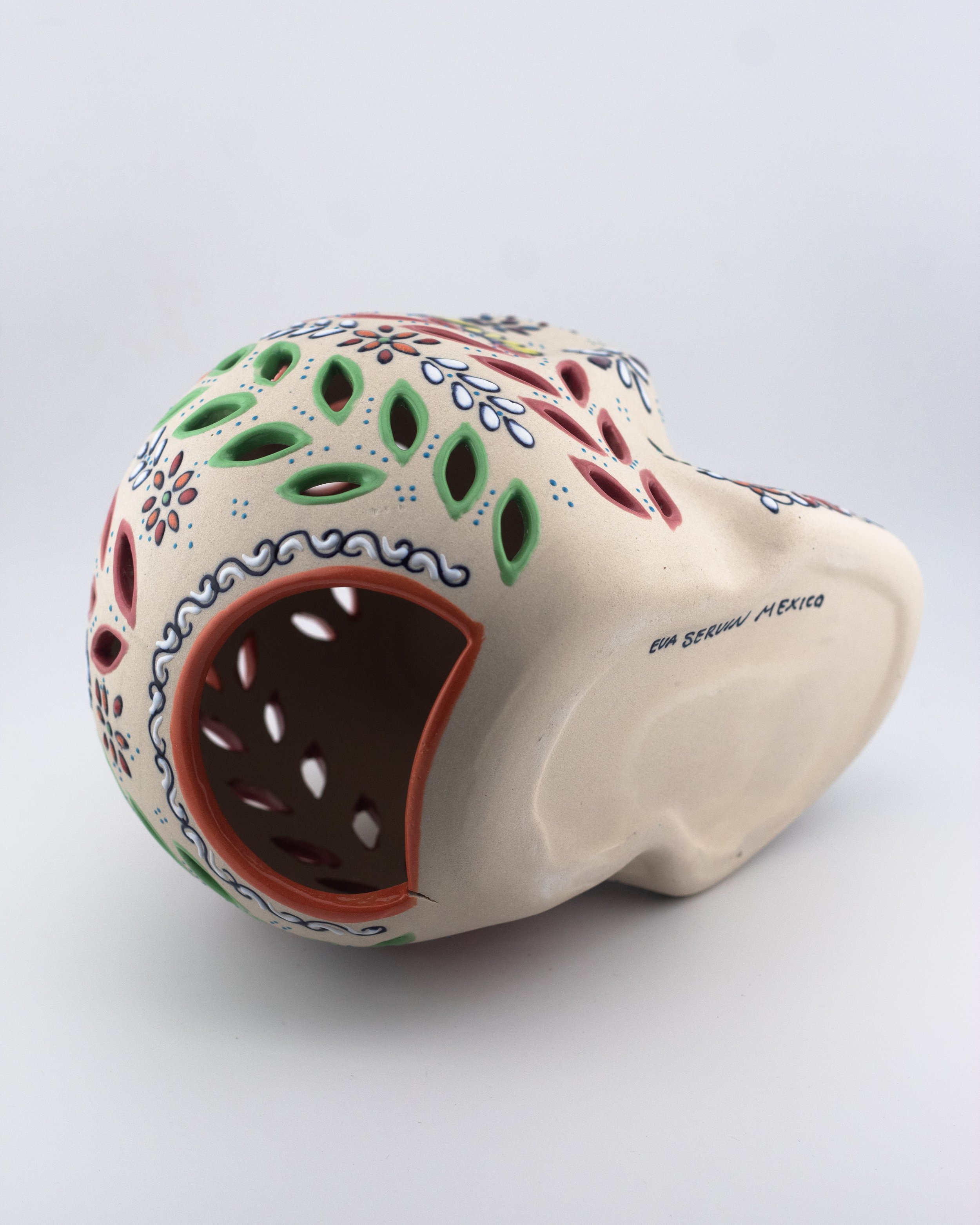 Calavera mexicana de cerámica artesanal decorativa con calado para colocar vela en el interior.