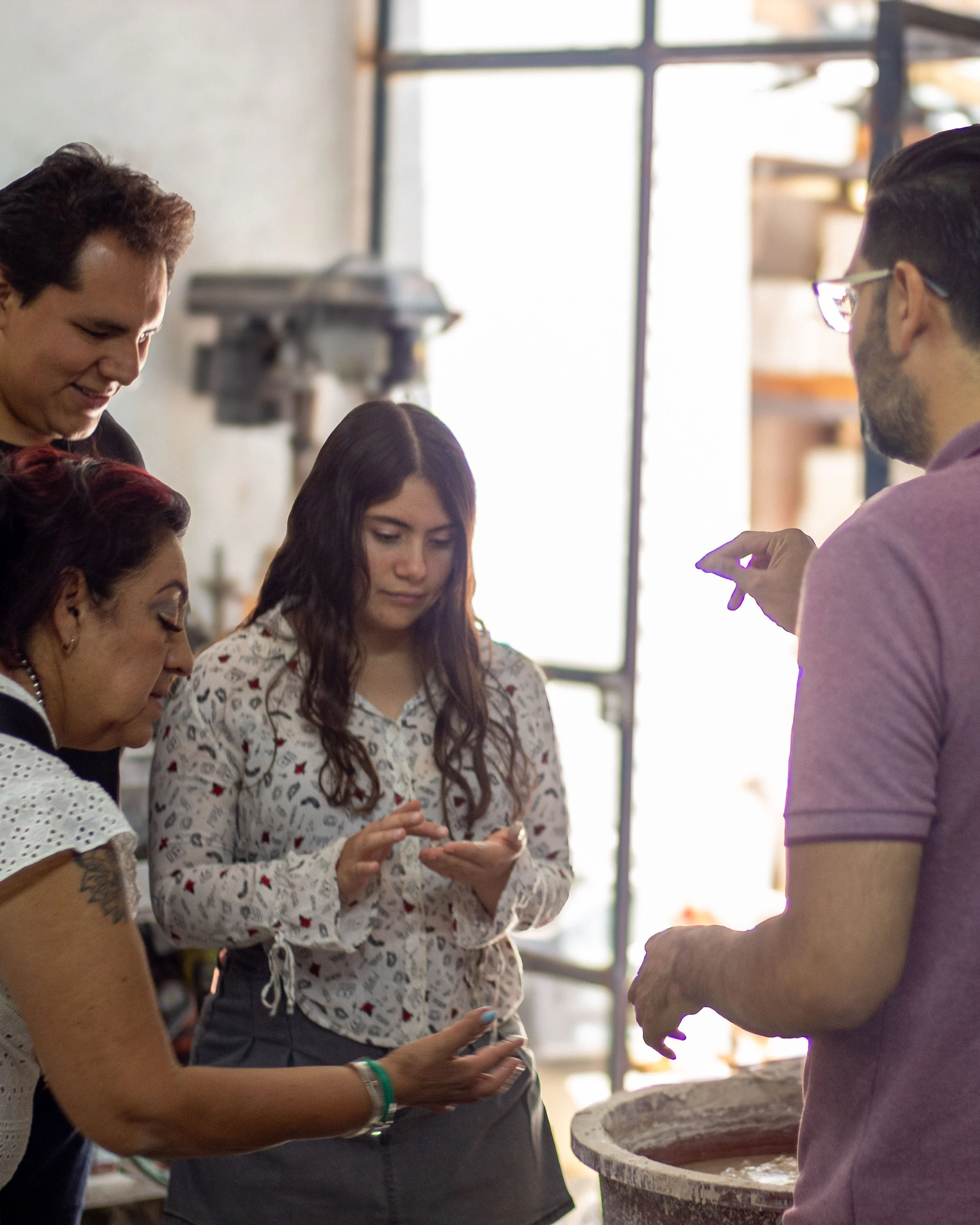 Un grupo de tres personas viendo la pasta que se usa en el taller de cerámica artesanal de Eva Servin, mientras el guía les está dando la explicación.