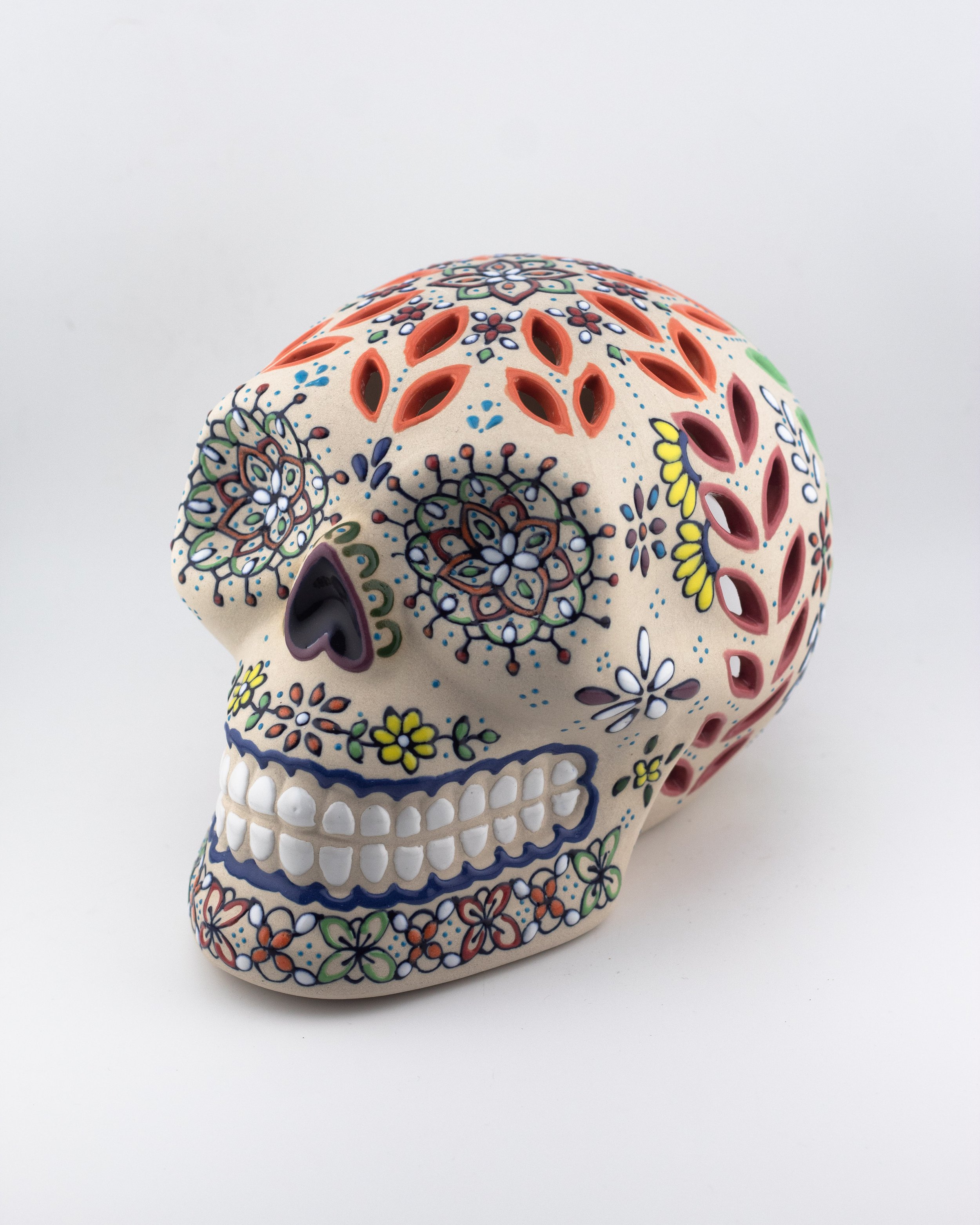 Calavera mexicana de cerámica artesanal decorativa con calado para colocar vela en el interior.