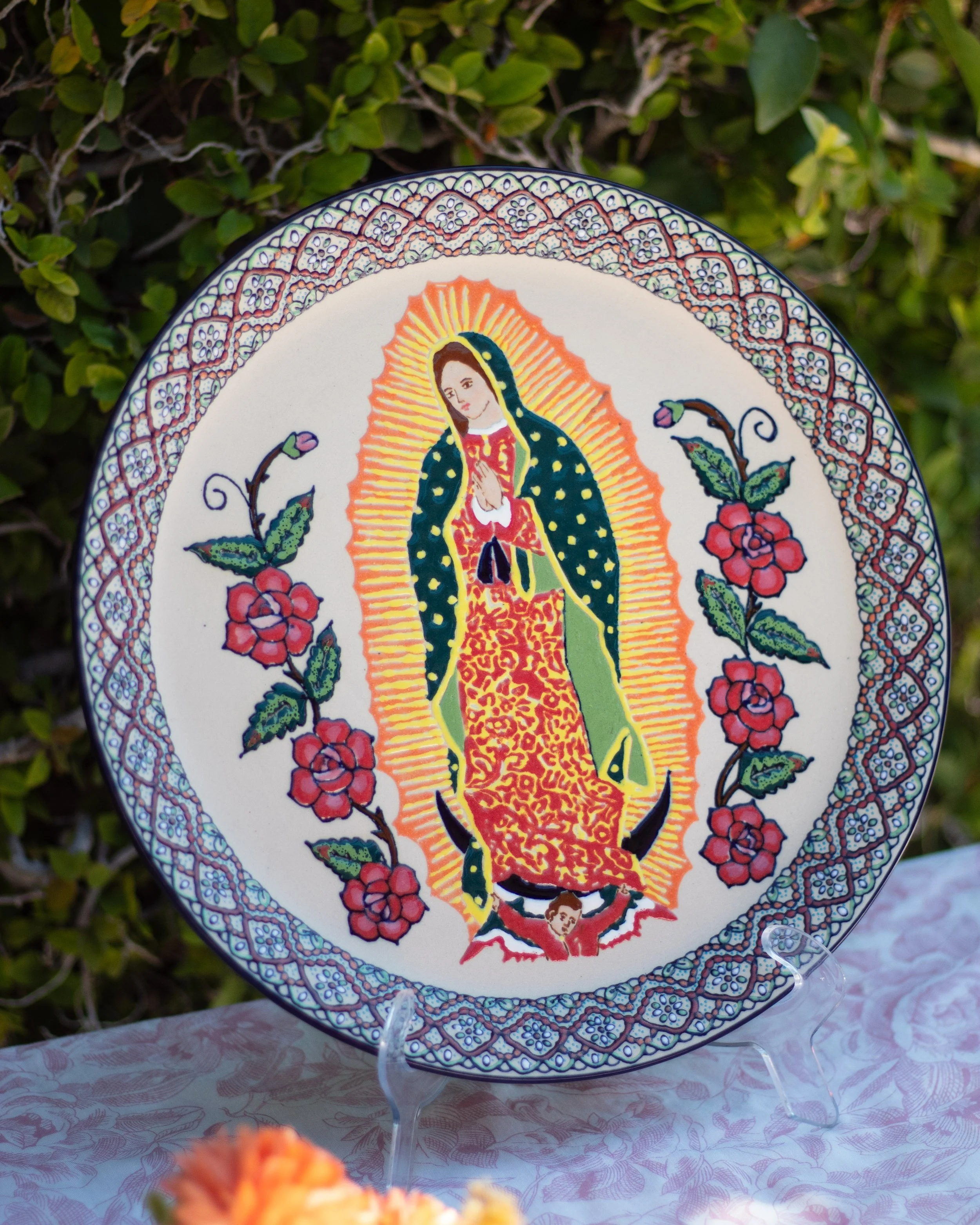 Plato decorado con imagen de la Virgen de Guadalupe rodeada de flores y borde decorativo.