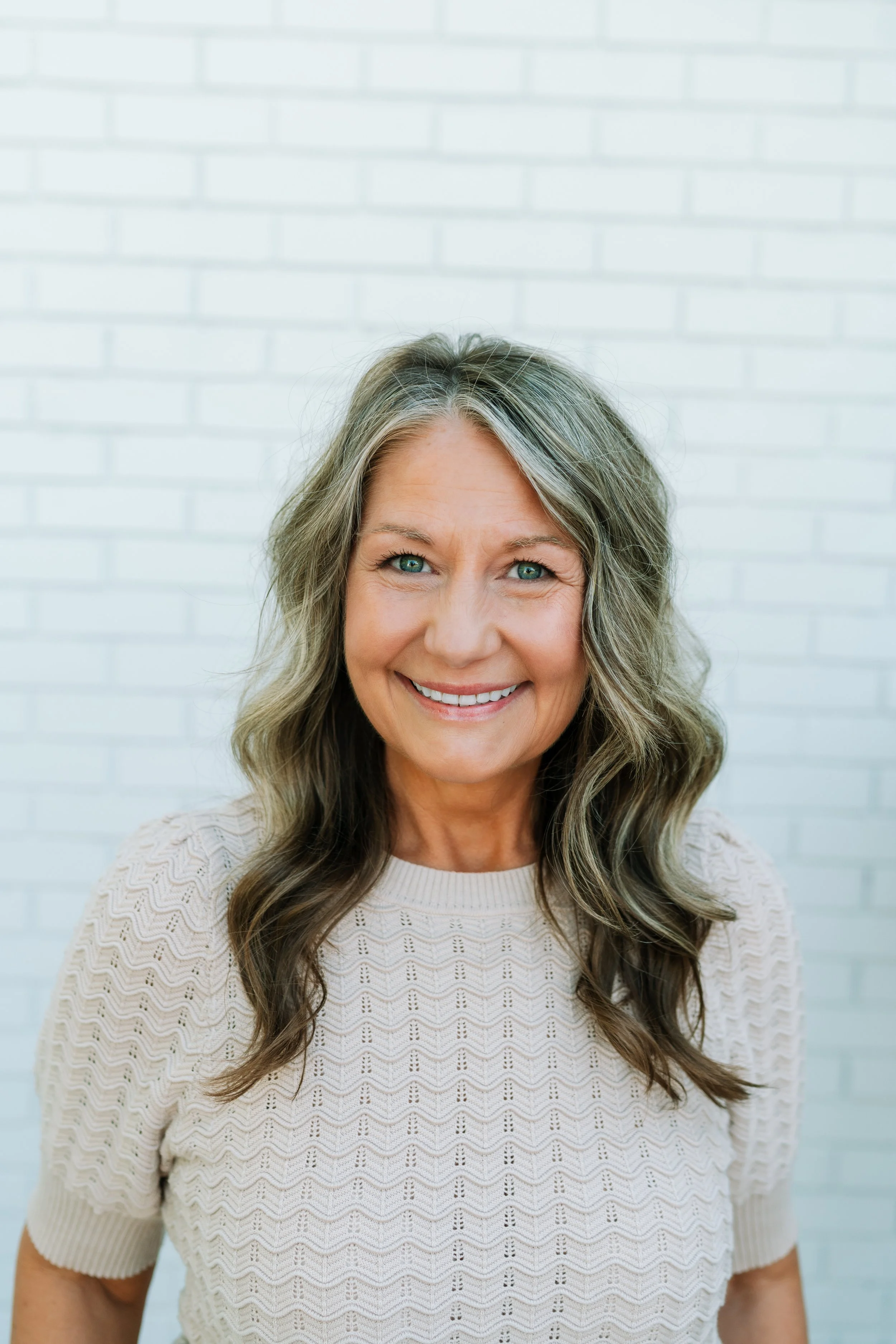 MaryLu has brown-to-blonde ombre hair and a crochet tan sweater