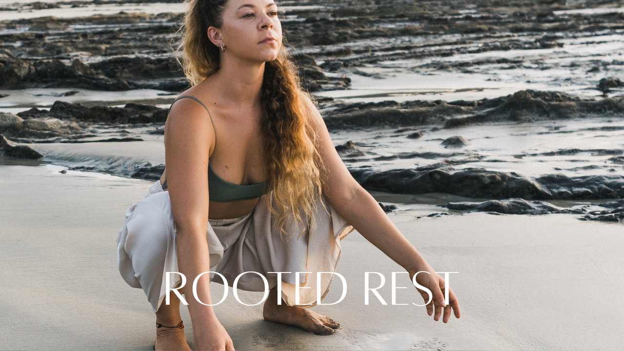 Woman with long hair practicing yoga on a sandy beach with rocks in the background, with the text 'Rooted Rest' overlaid.