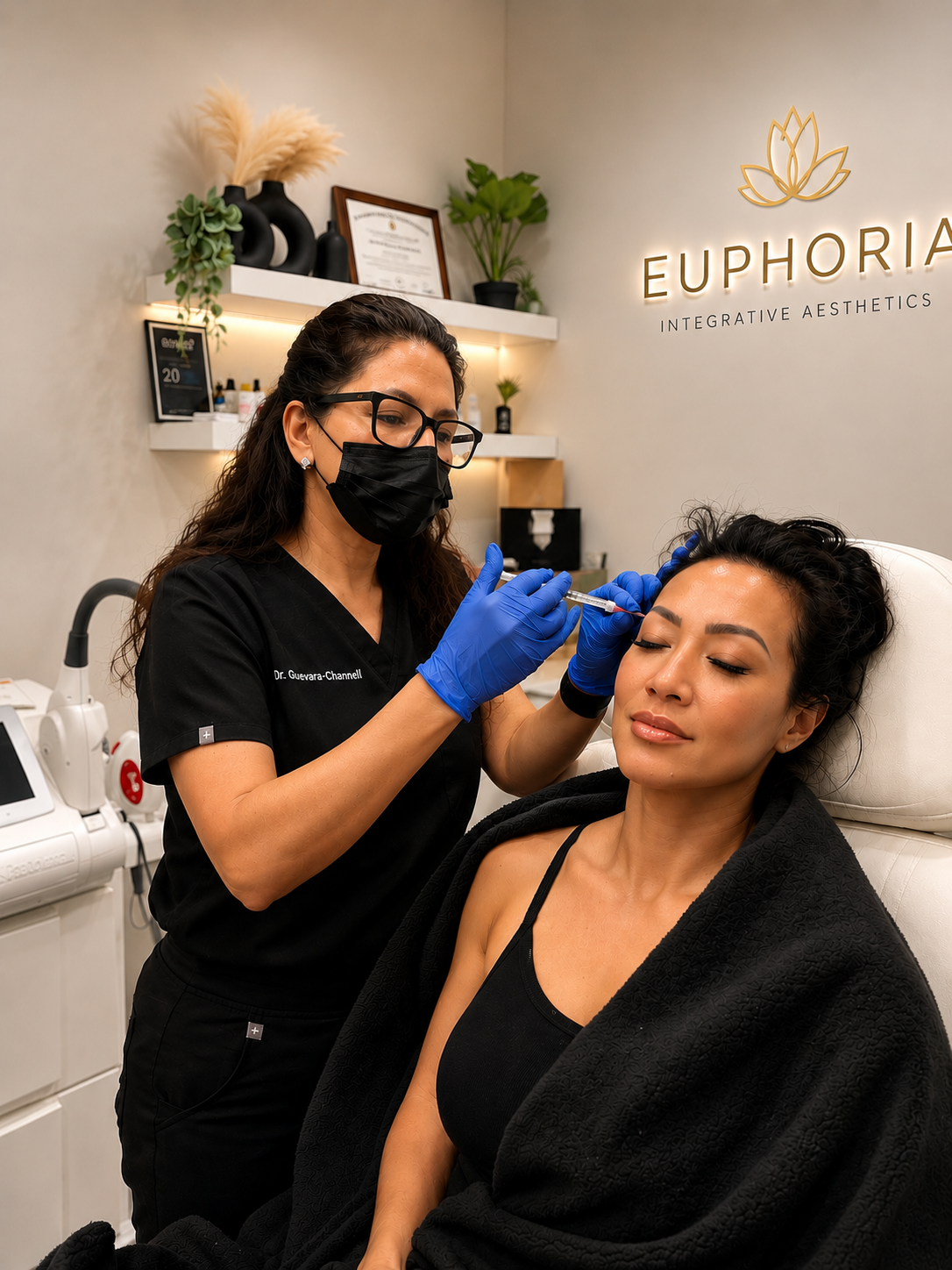A woman receiving a cosmetic injectable treatment from a practitioner at Euphoria Integrative Aesthetics, with shelves and decor in the background.