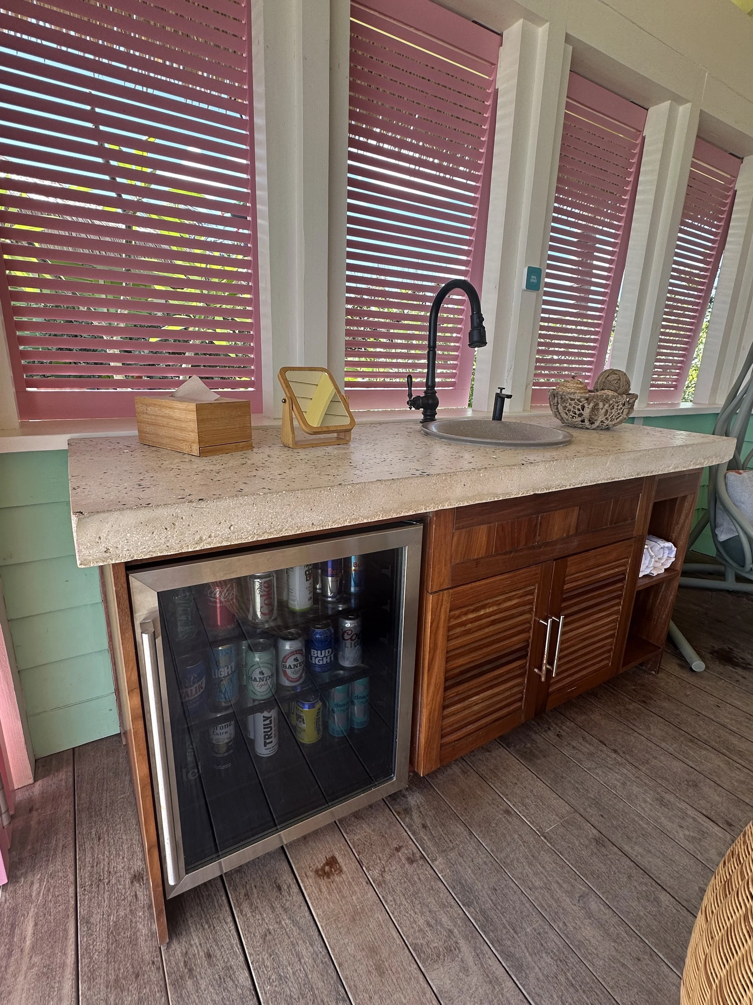 : Cabana mini bar with a stocked drinks fridge, sink, and counter space.