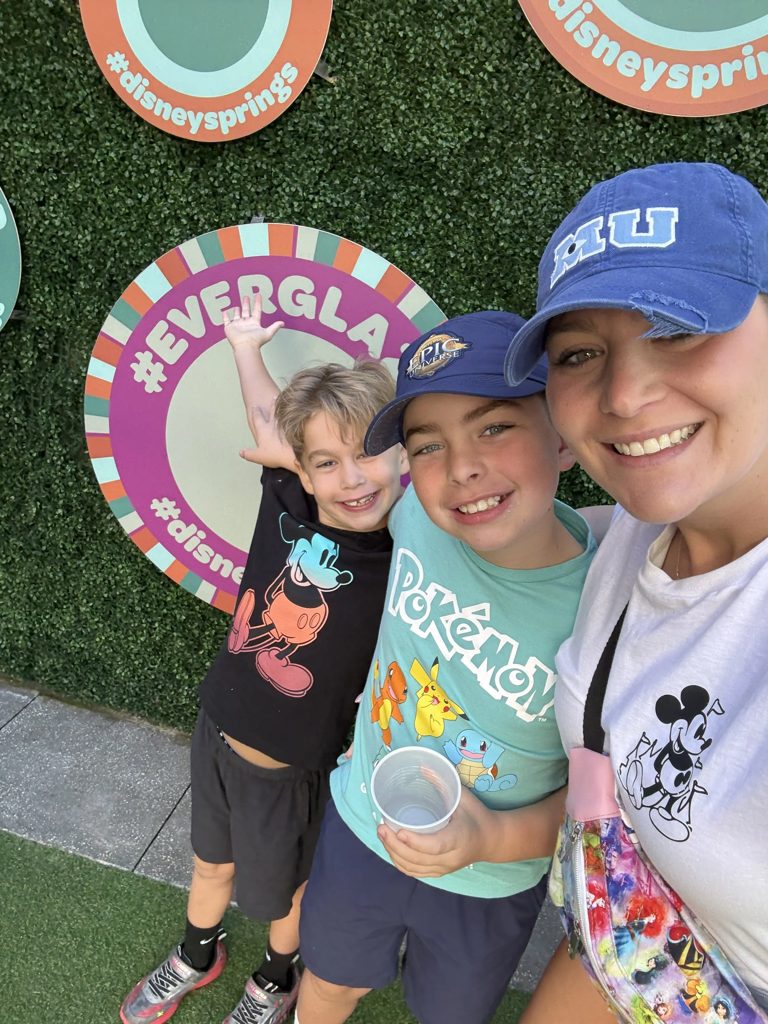 a mom and her two kids in front of a sign that says everglaze donuts