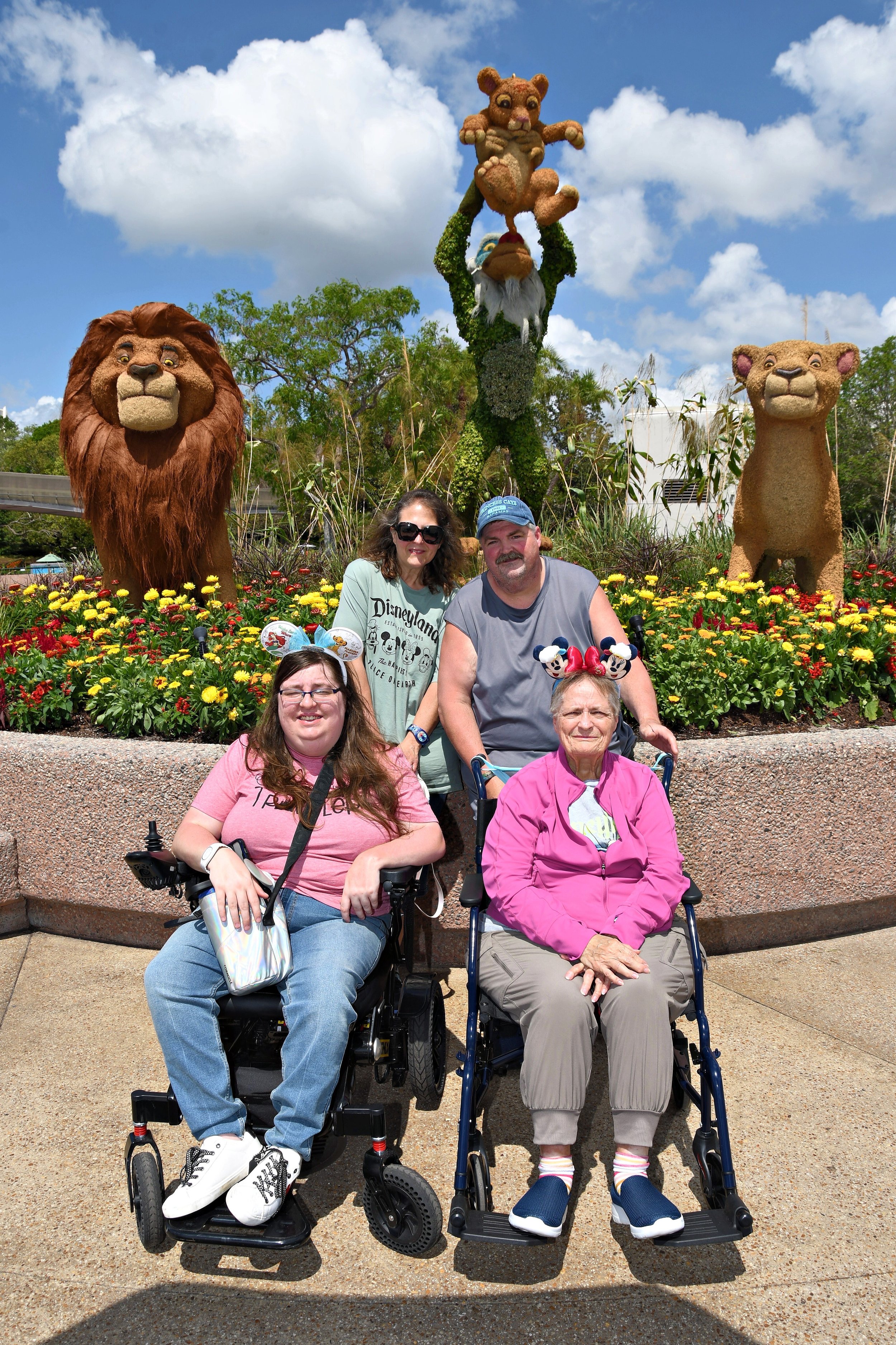 family at flower & garden festival at epcot standing in front of a lion king topiary. two of the guests are in wheelchairs