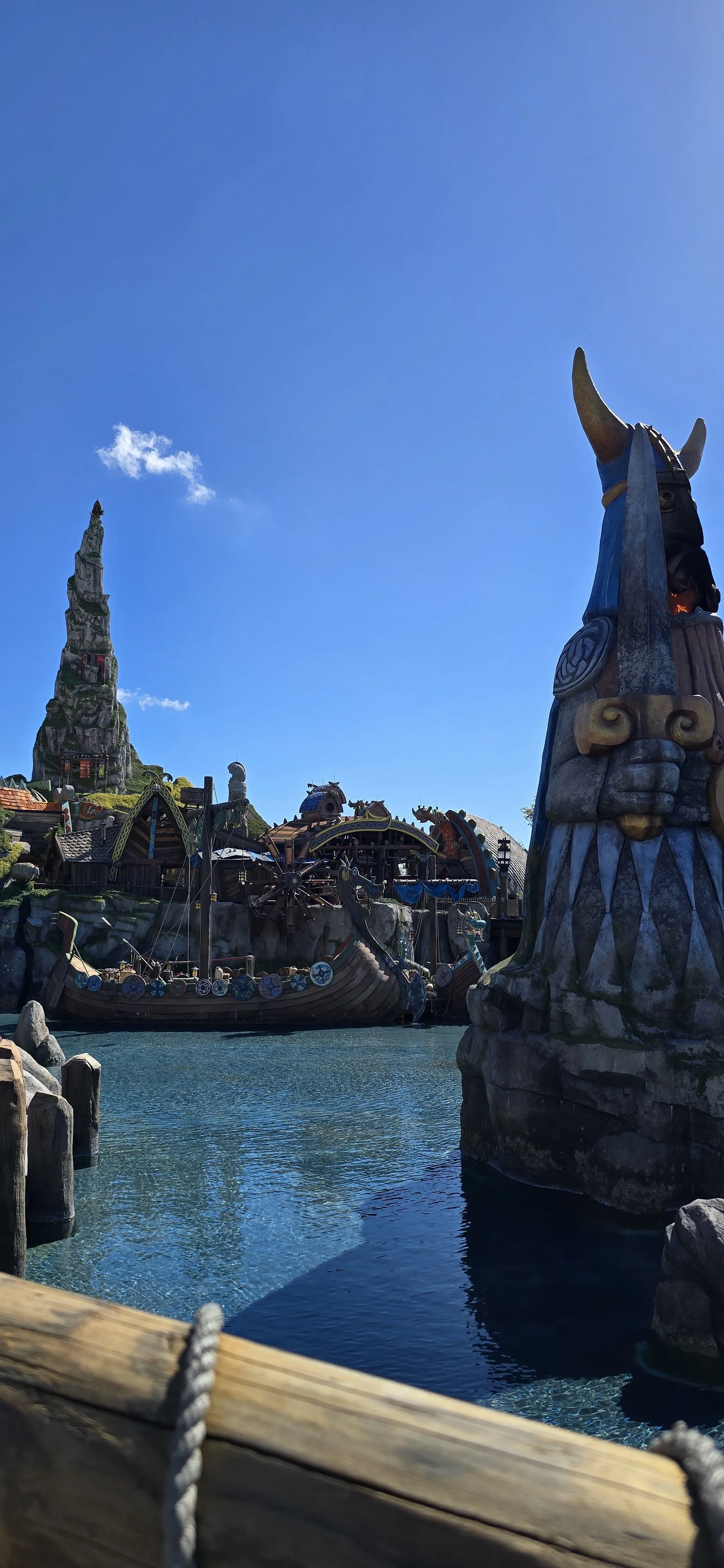 dragon styled boats on a small lake with house and a large mountain in the background