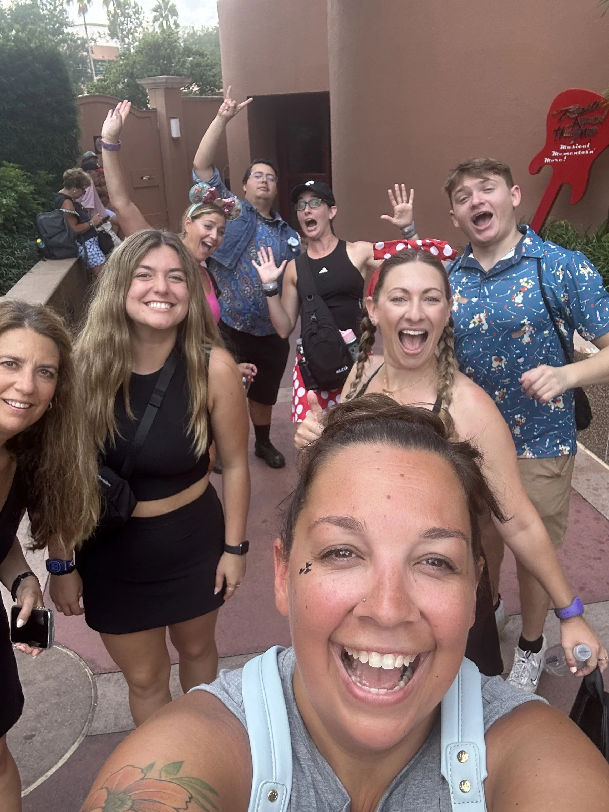 Darcy Roy celebrating with a group of friends outside the Rock 'n' Roller Coaster entrance at Disney's Hollywood Studios.