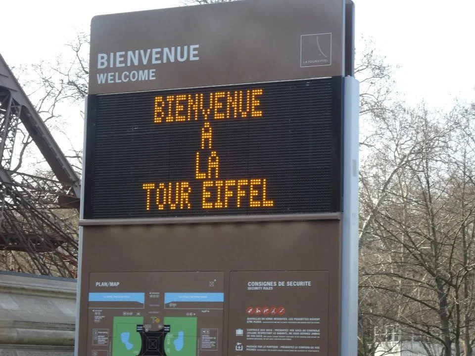 Illuminated welcome sign at the base of the Eiffel Tower reading "Bienvenue à la Tour Eiffel."
