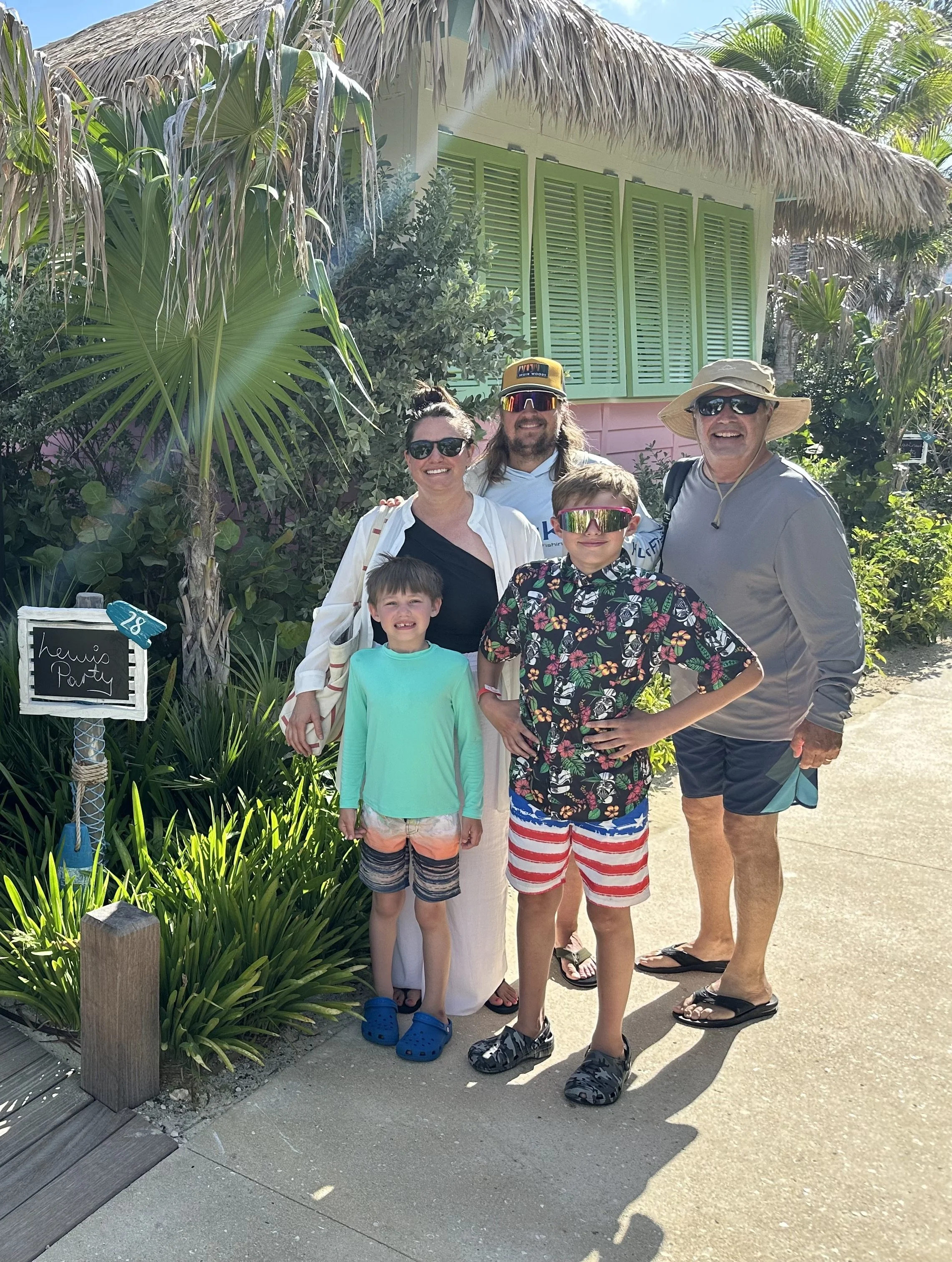 Family posing outside their reserved cabana, marked with a "Lewis Party" sign, at Royal Beach Club Paradise Island